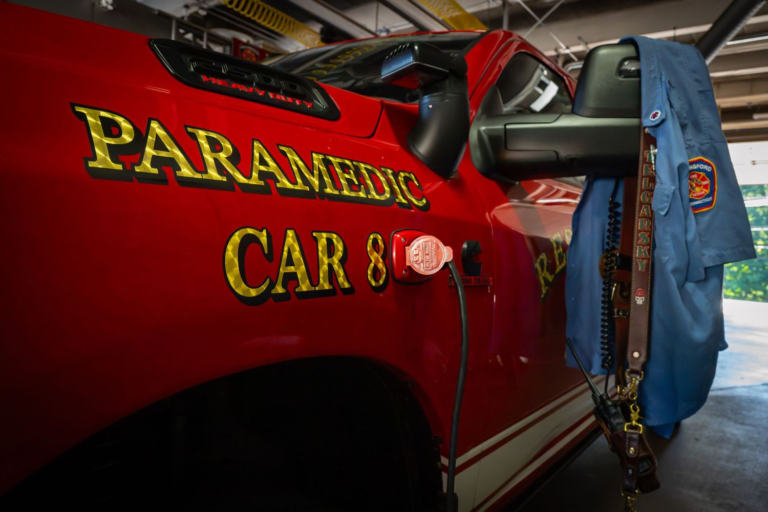 Red paramedic car 8 vehicle with yellow lettering and a uniform jacket hanging on the open door.