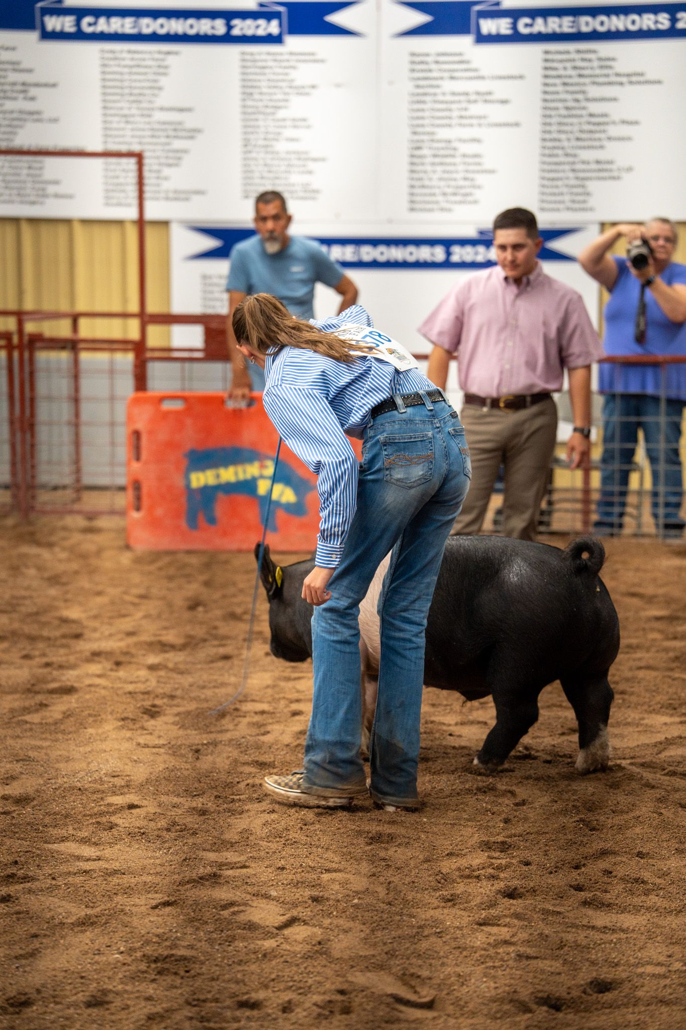 Sequence showing a goat being led and shown in a dirt arena at a livestock competition.