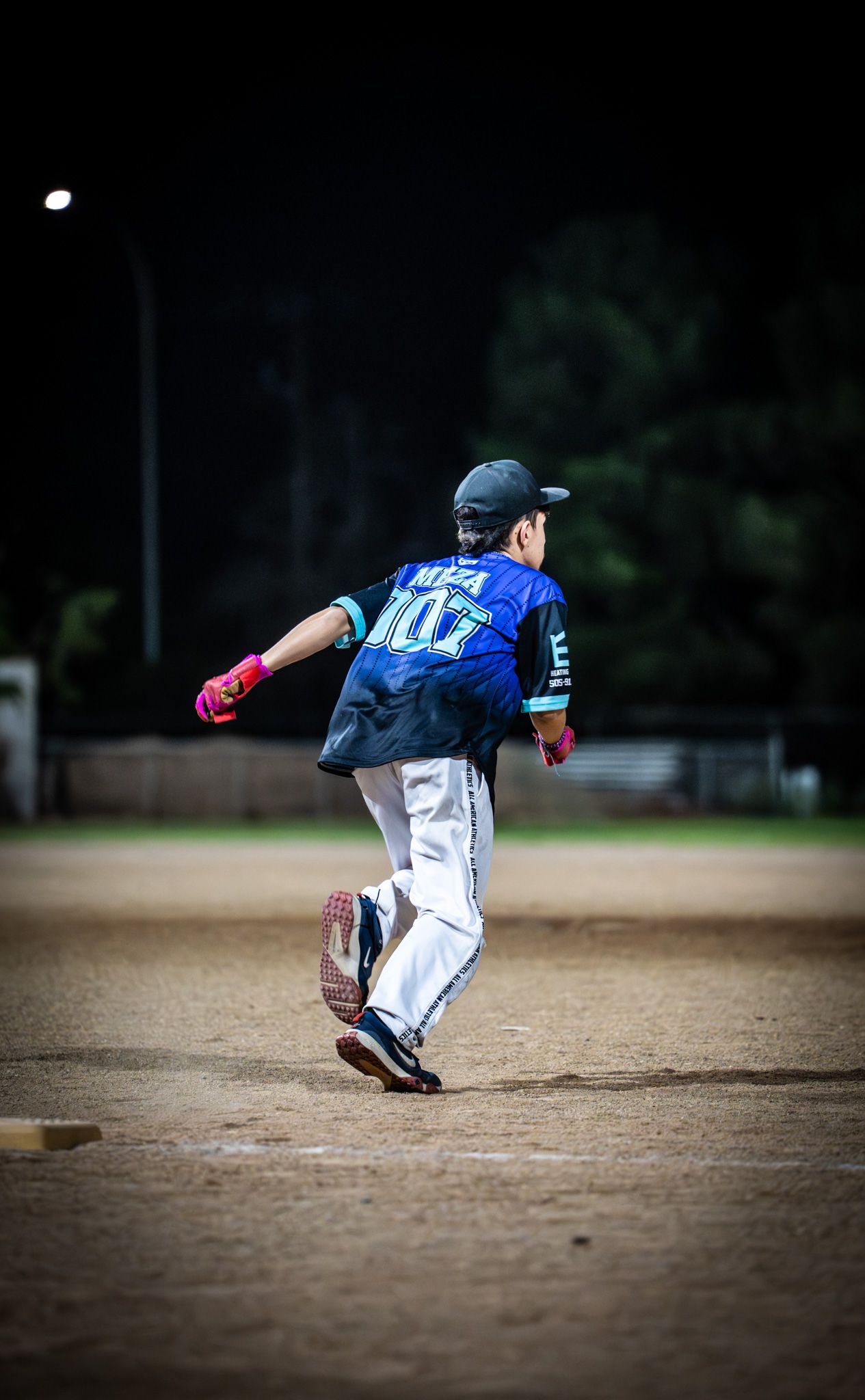 Baseball player in blue jersey sliding into base during a game on a dirt infield.
