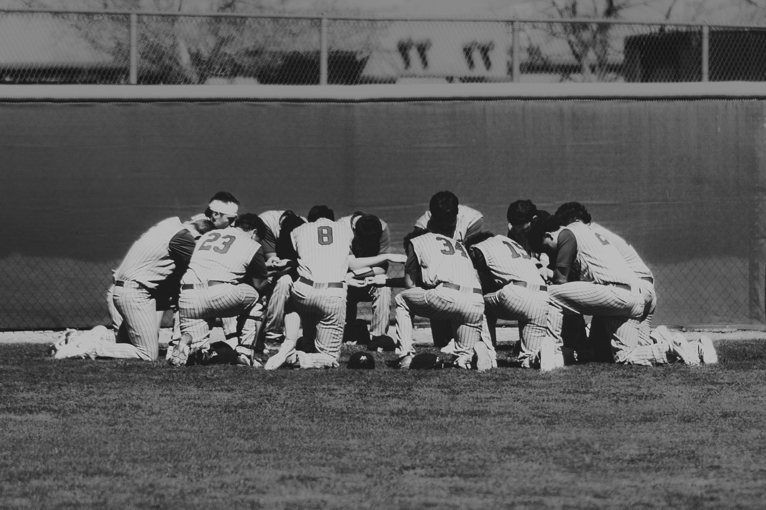 Baseball players lie on the ground in a row during a practice or training session on a baseball field.