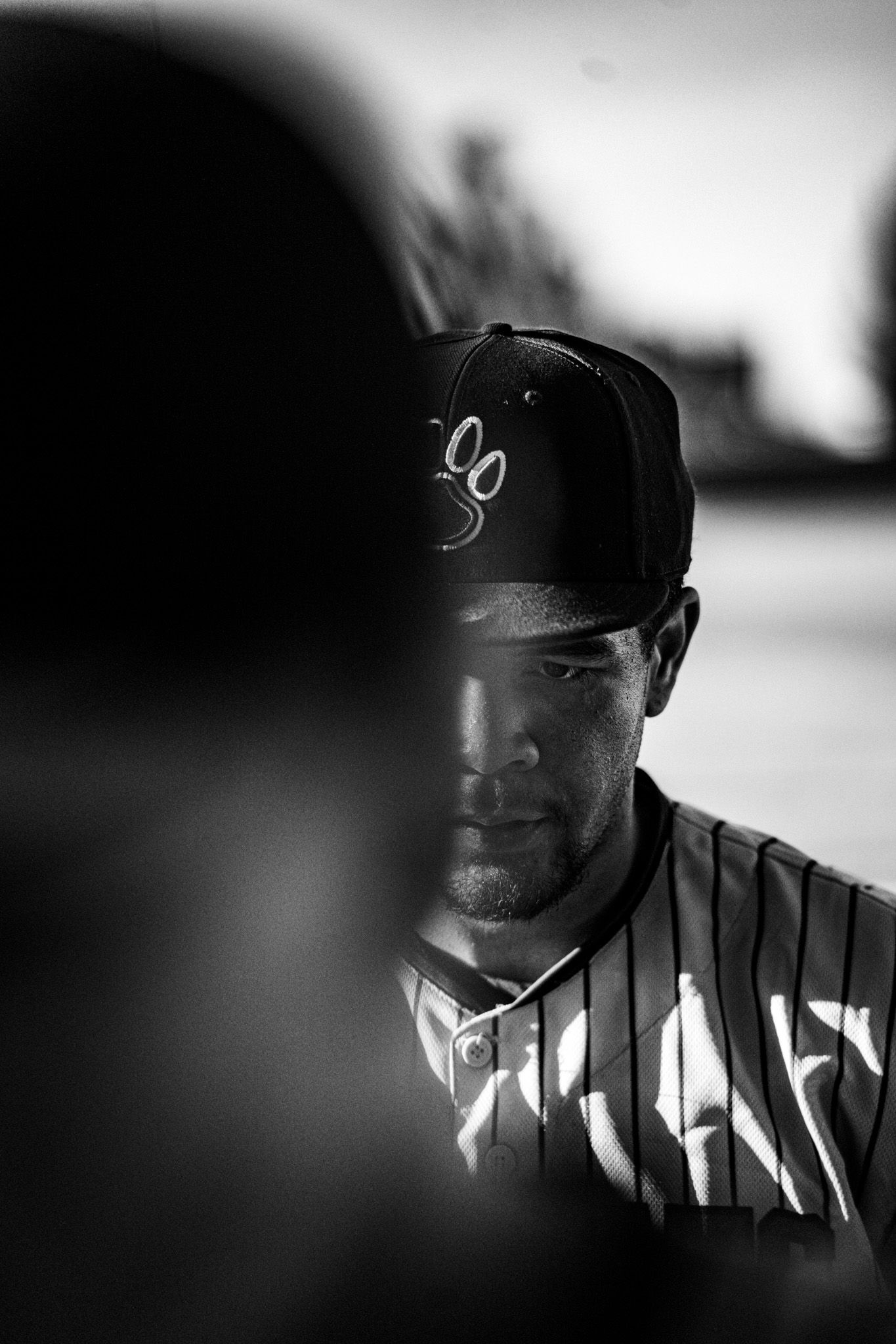 Dramatic black and white profile shots of baseball players wearing caps against a blurred background.