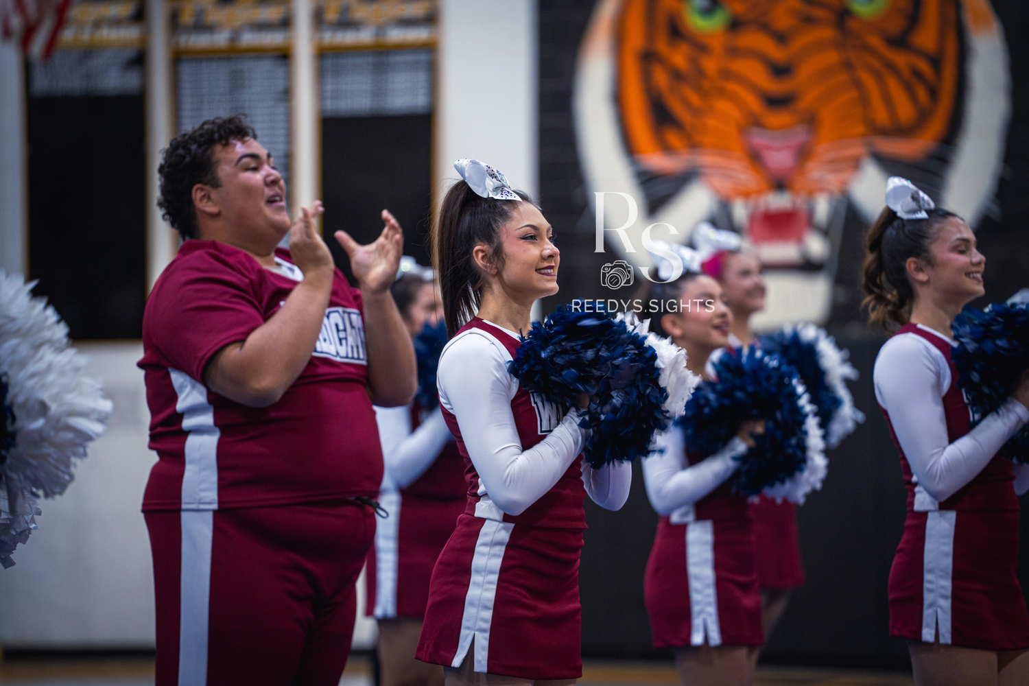 Students in maroon uniforms perform a spirited cheerleading routine during a school event.
