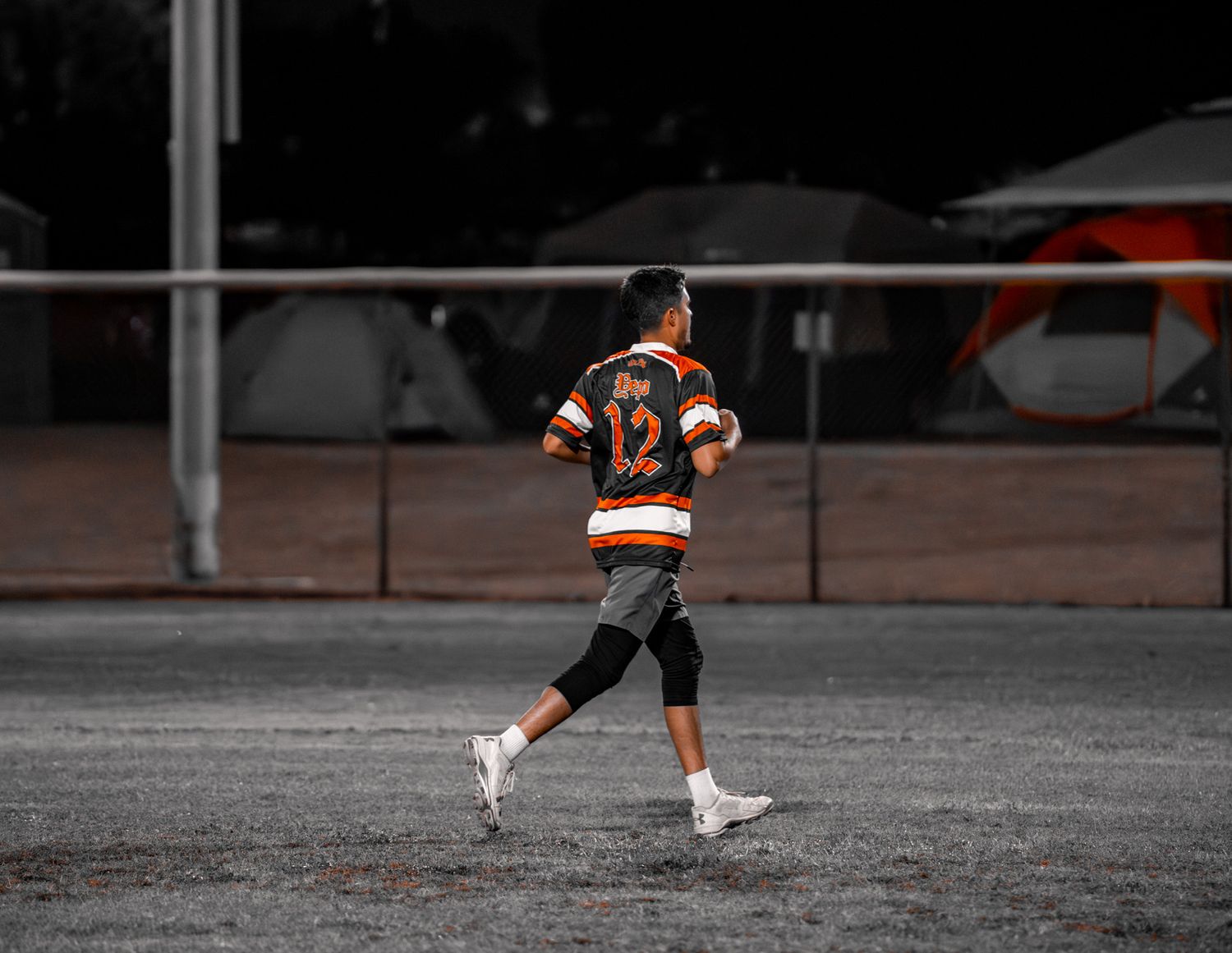 Baseball player in orange and black uniform slides into base during game on dirt infield.