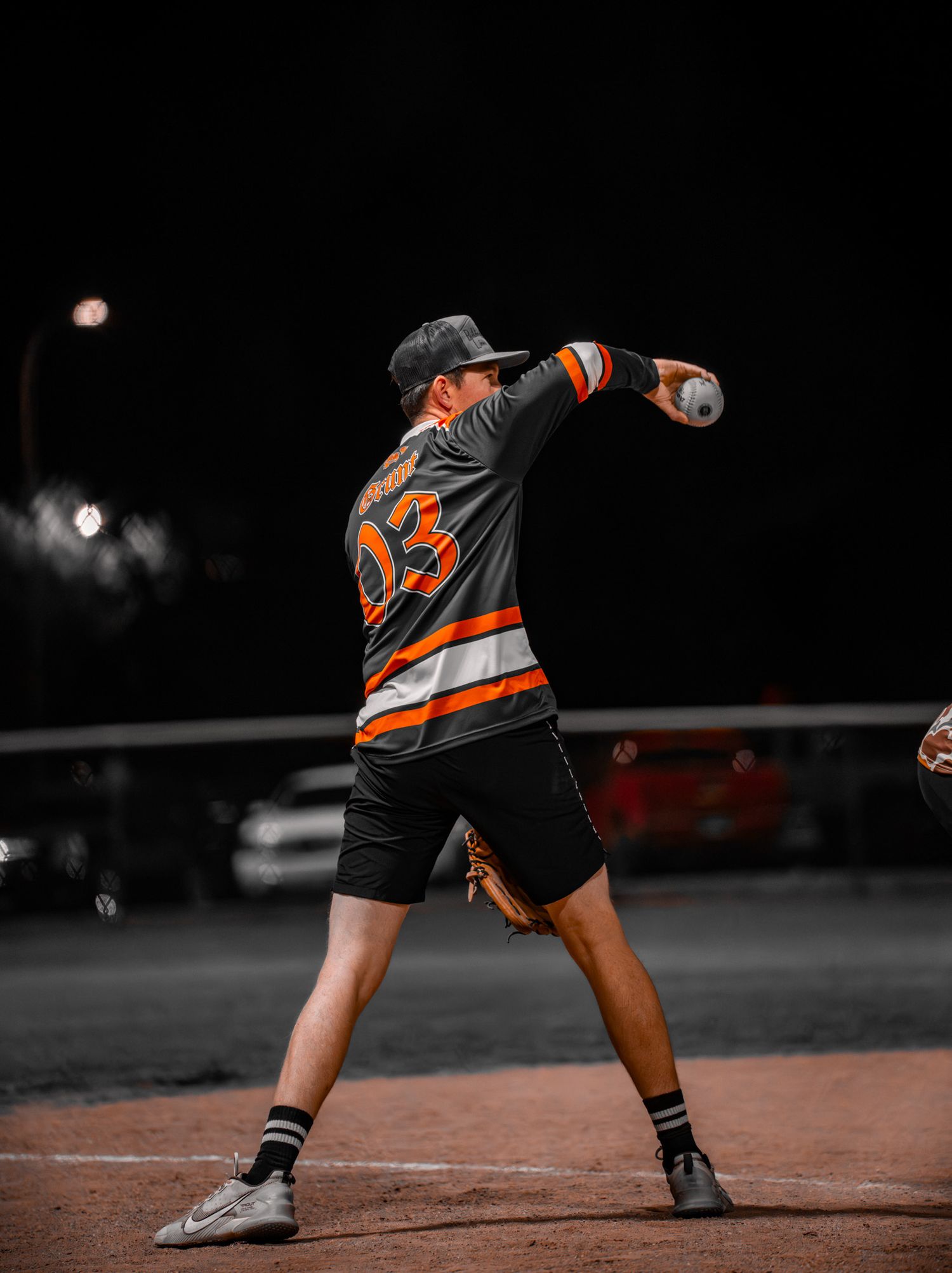 Baseball player wearing orange and black uniform slides into base during dramatic night game play.