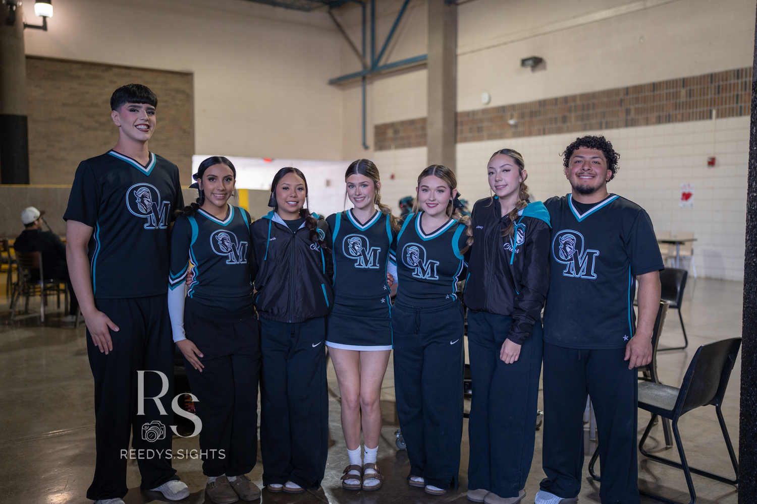 A group of seven people wearing matching dark blue uniforms stand together for a team photo.