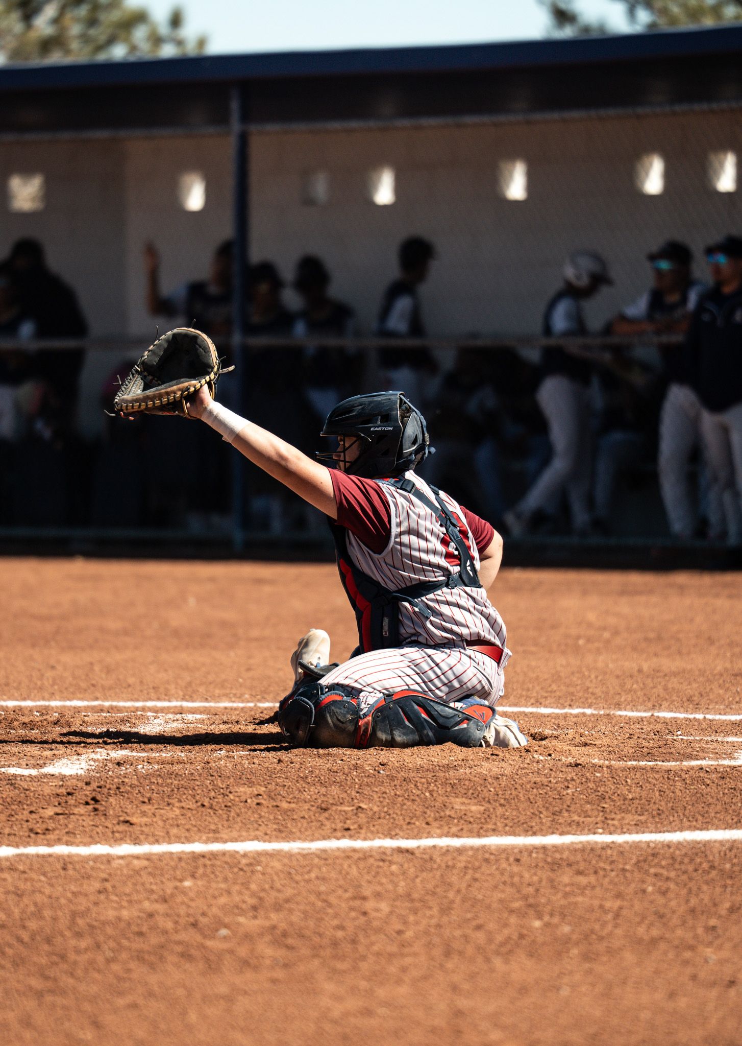 Baseball player makes a dramatic sliding catch on the infield dirt during a game.
