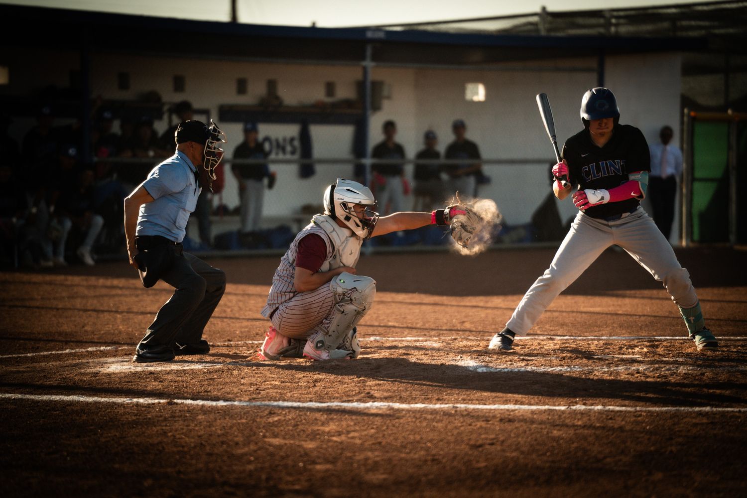 Baseball player slides into base during intense game action on dirt infield.