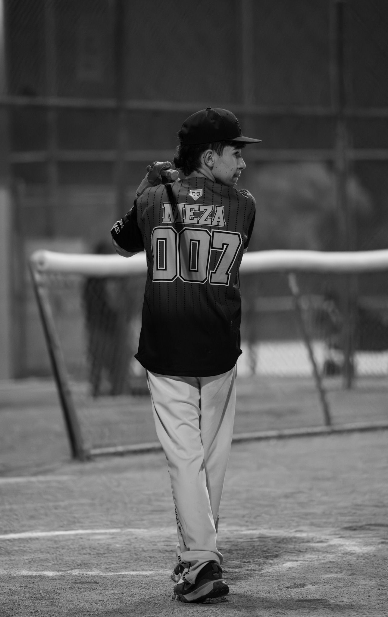 Black and white photo of a baseball player wearing jersey number 007 viewed from behind on a baseball field.
