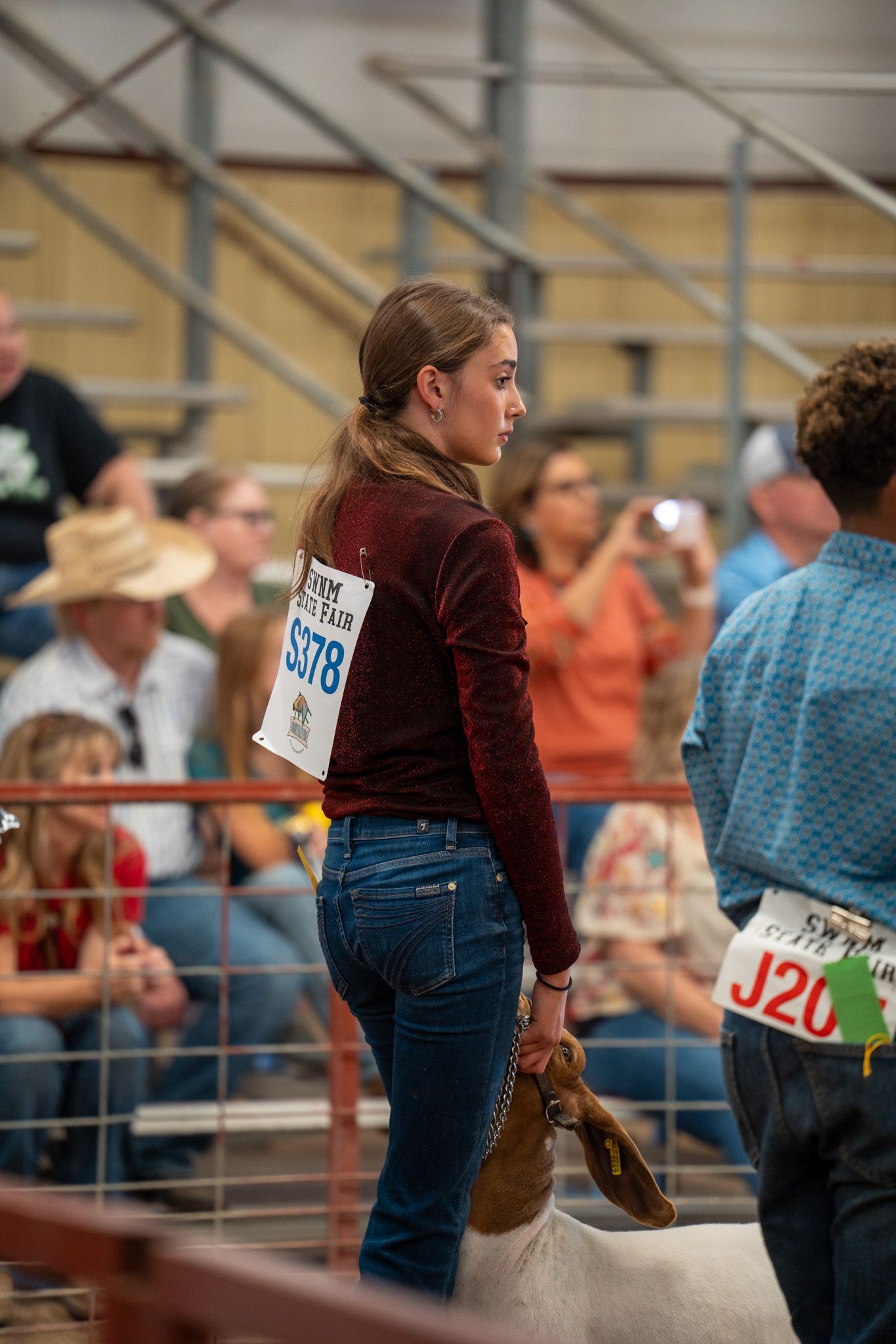 Competitor with number tag walking through an indoor arena during a livestock show event.
