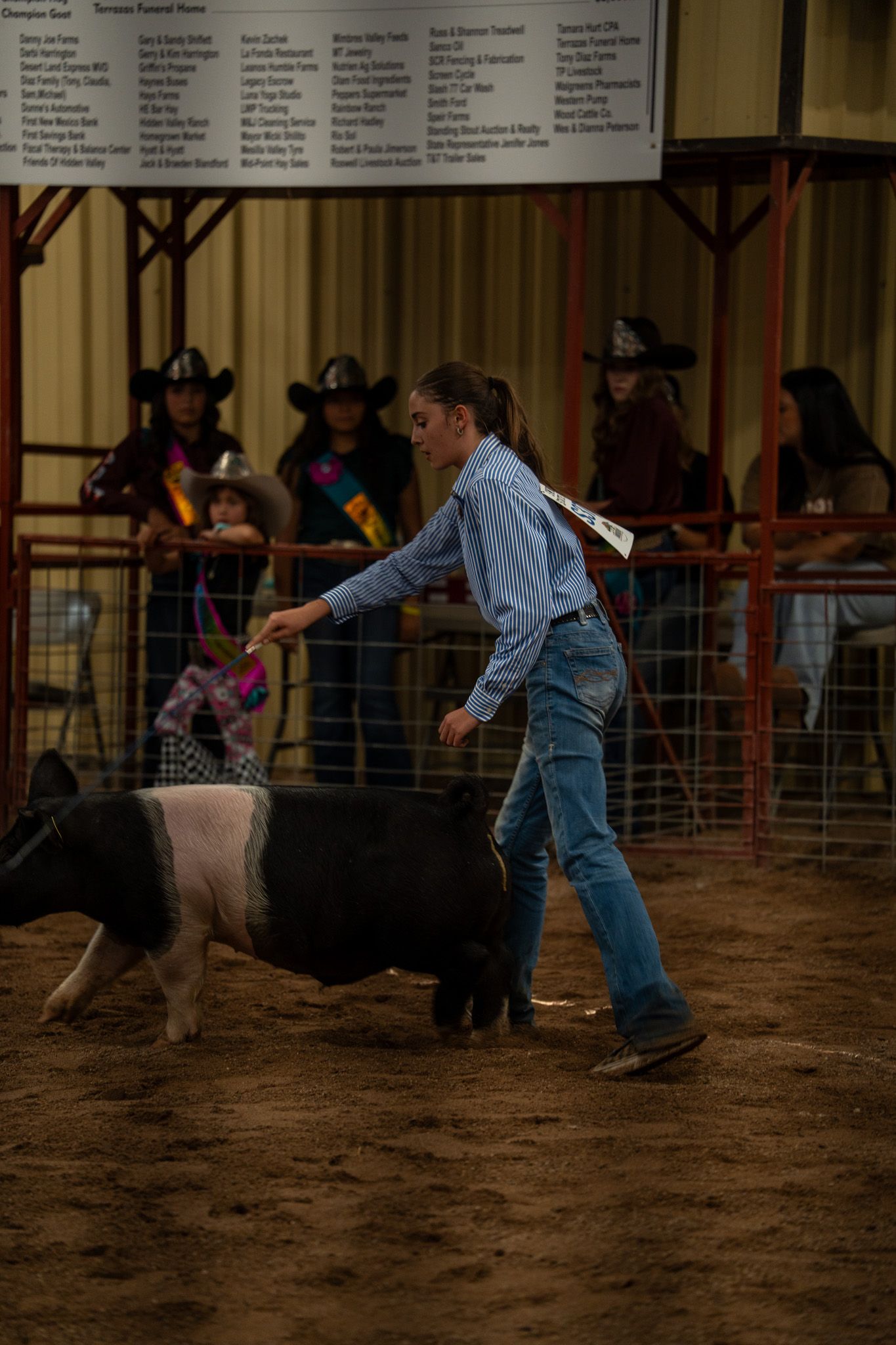 Rodeo participants practice roping techniques in a dirt arena during a training session.