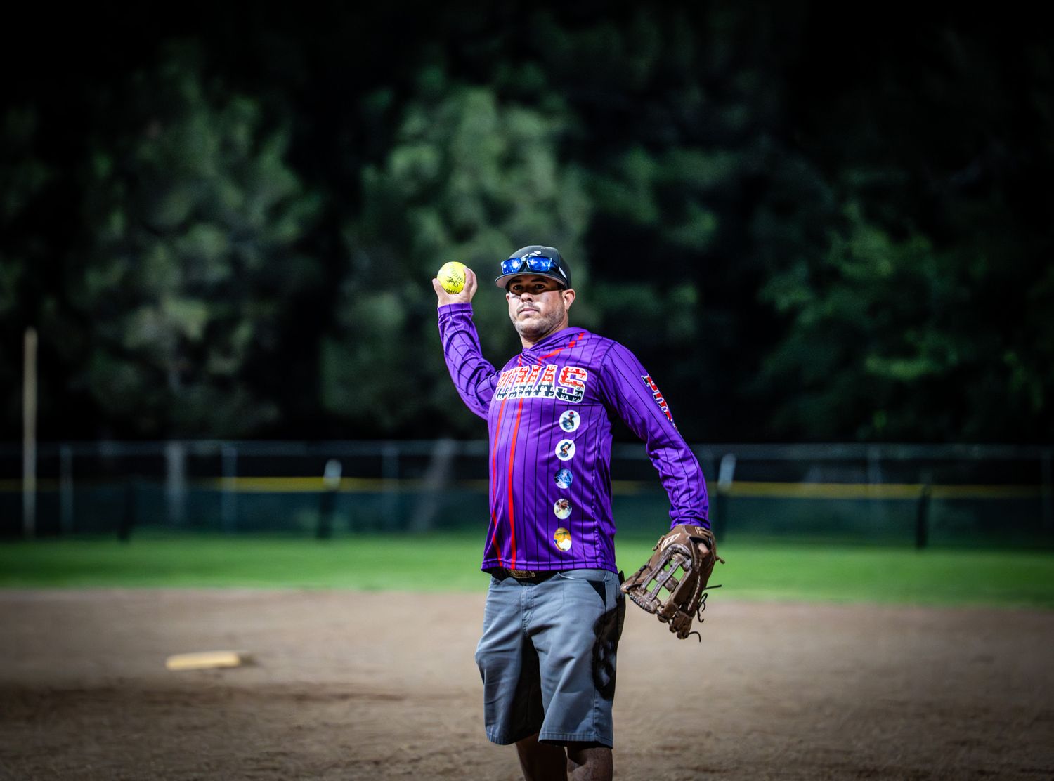 Youth softball players in purple jerseys practicing on baseball diamond.