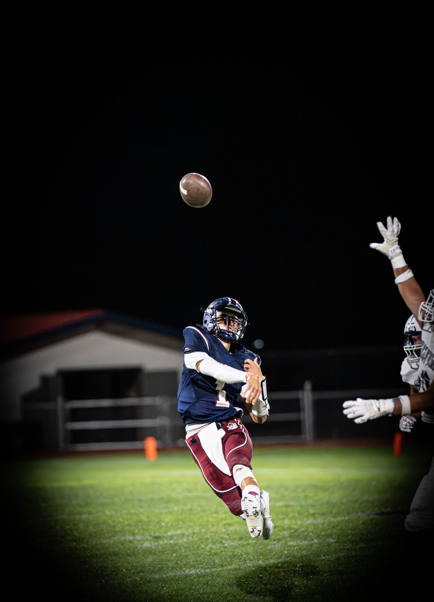 Football player making dramatic diving catch under stadium lights at night.