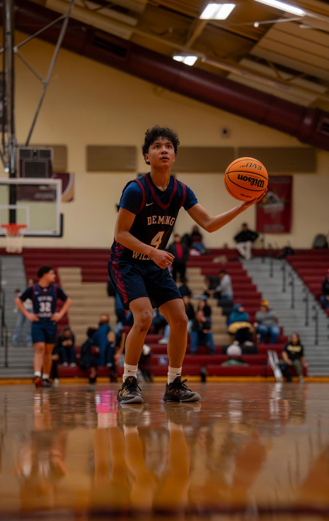 Young basketball players in blue uniforms practice dribbling drills on a wooden court.