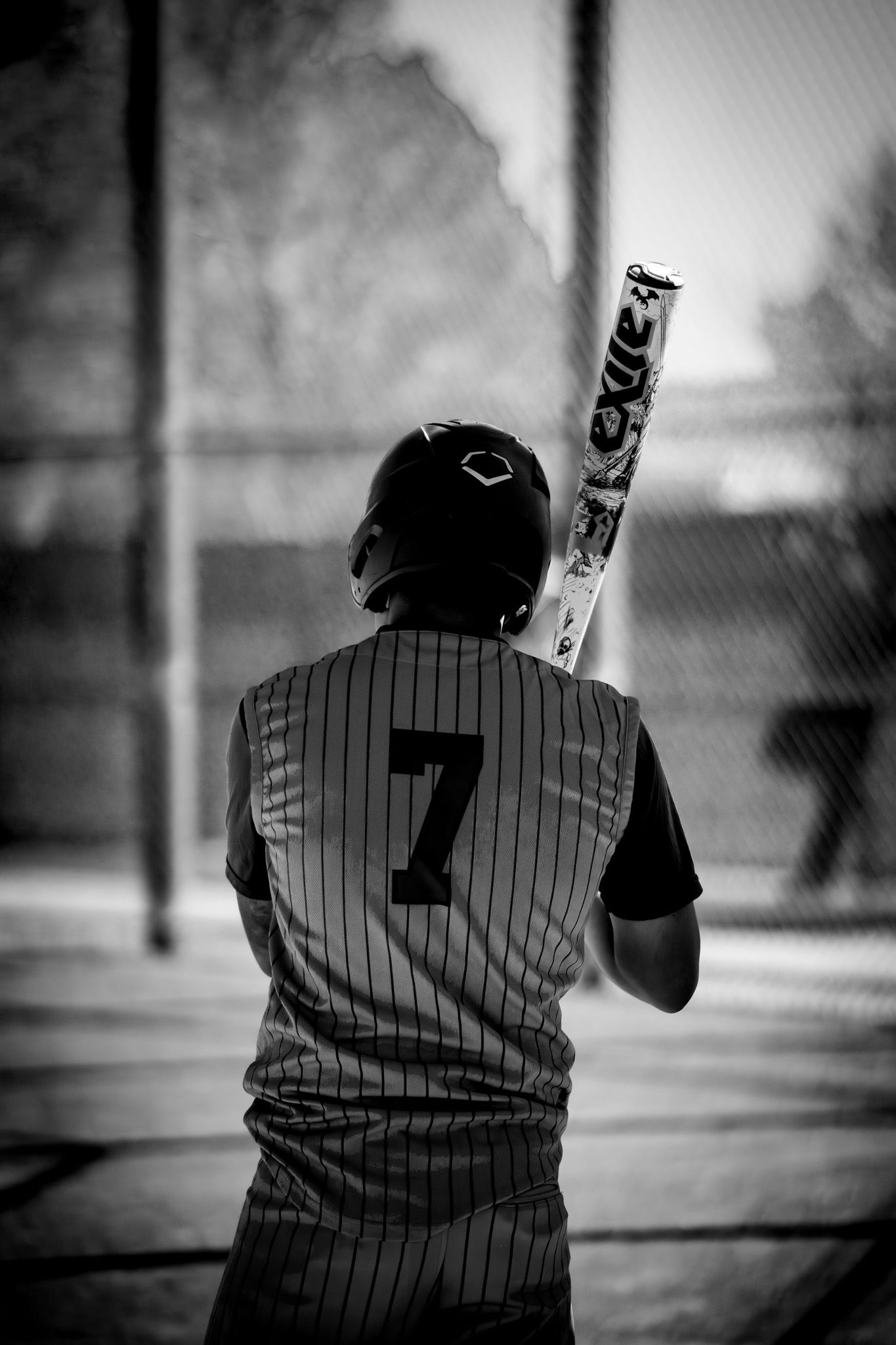 Baseball player in pinstriped jersey number 7 stands at bat in black and white photography.