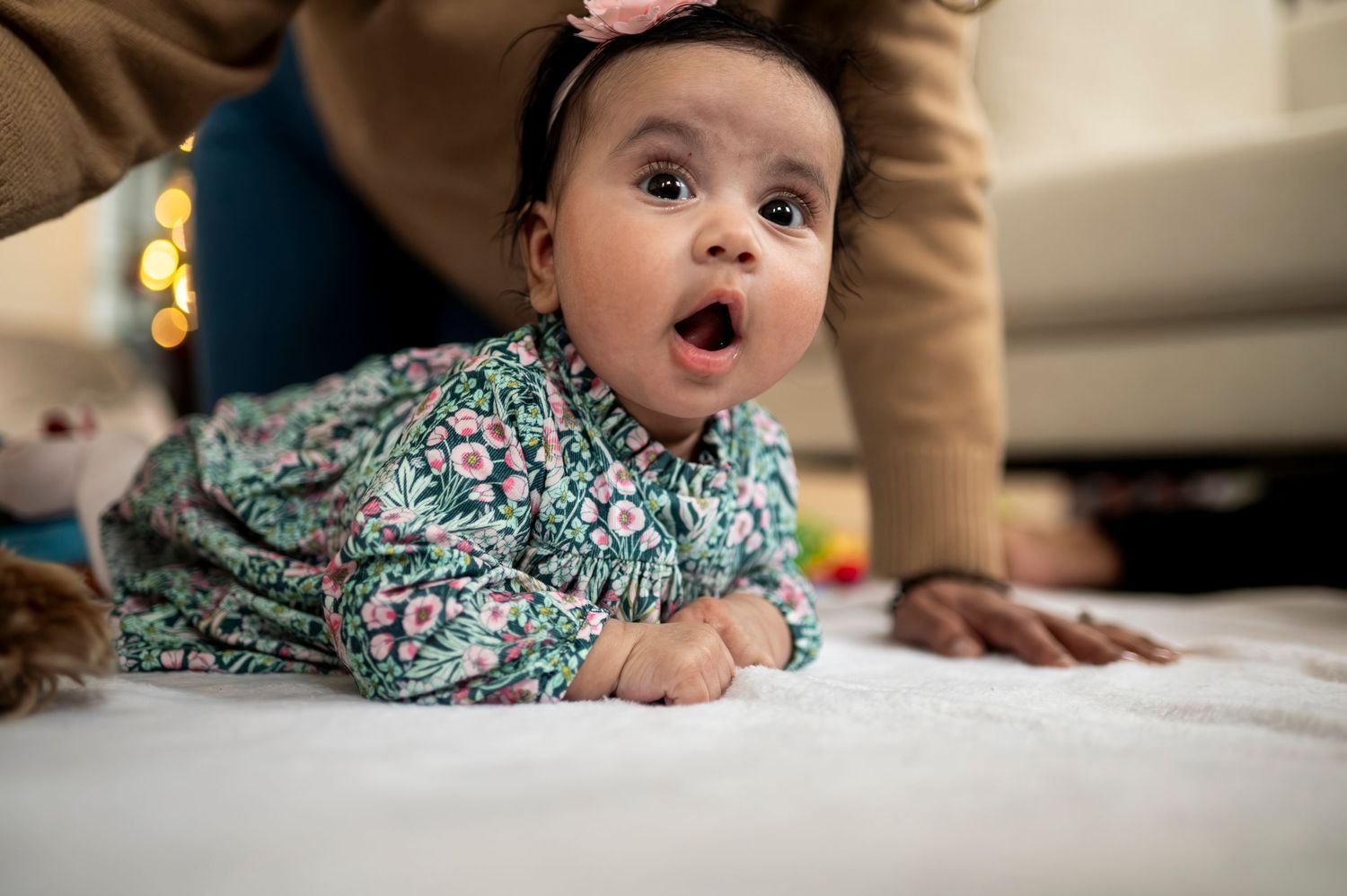 Baby girl makes surprised face as she plays during tummy time at home.