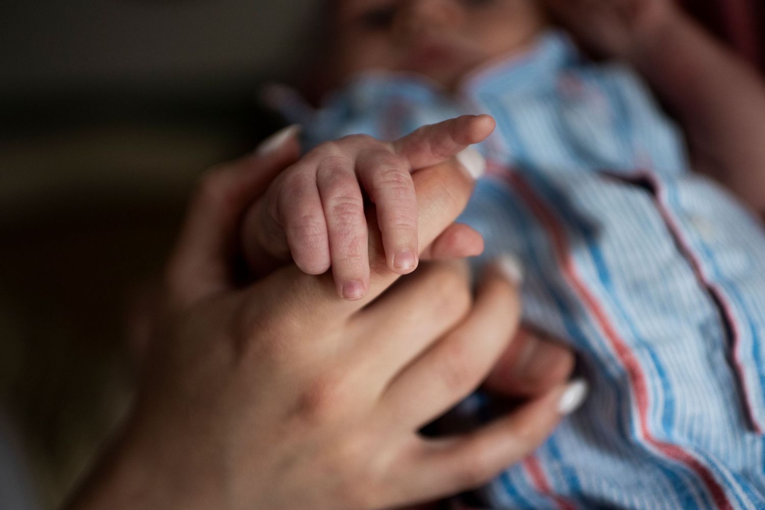 Close up of newborn baby's hand holding mother's finger.
