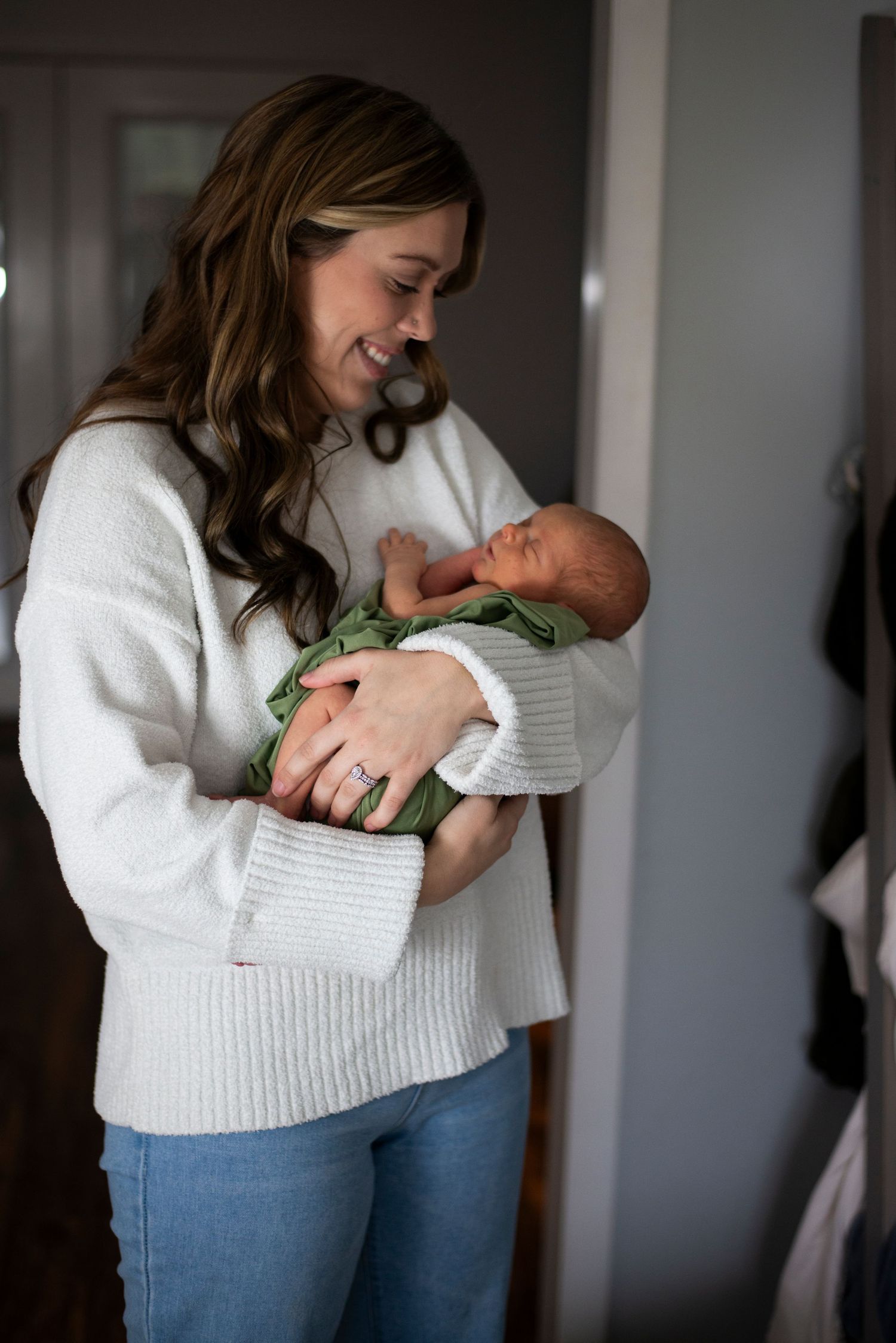 New mother smiles and holds her newborn son in her home in New Jersey.