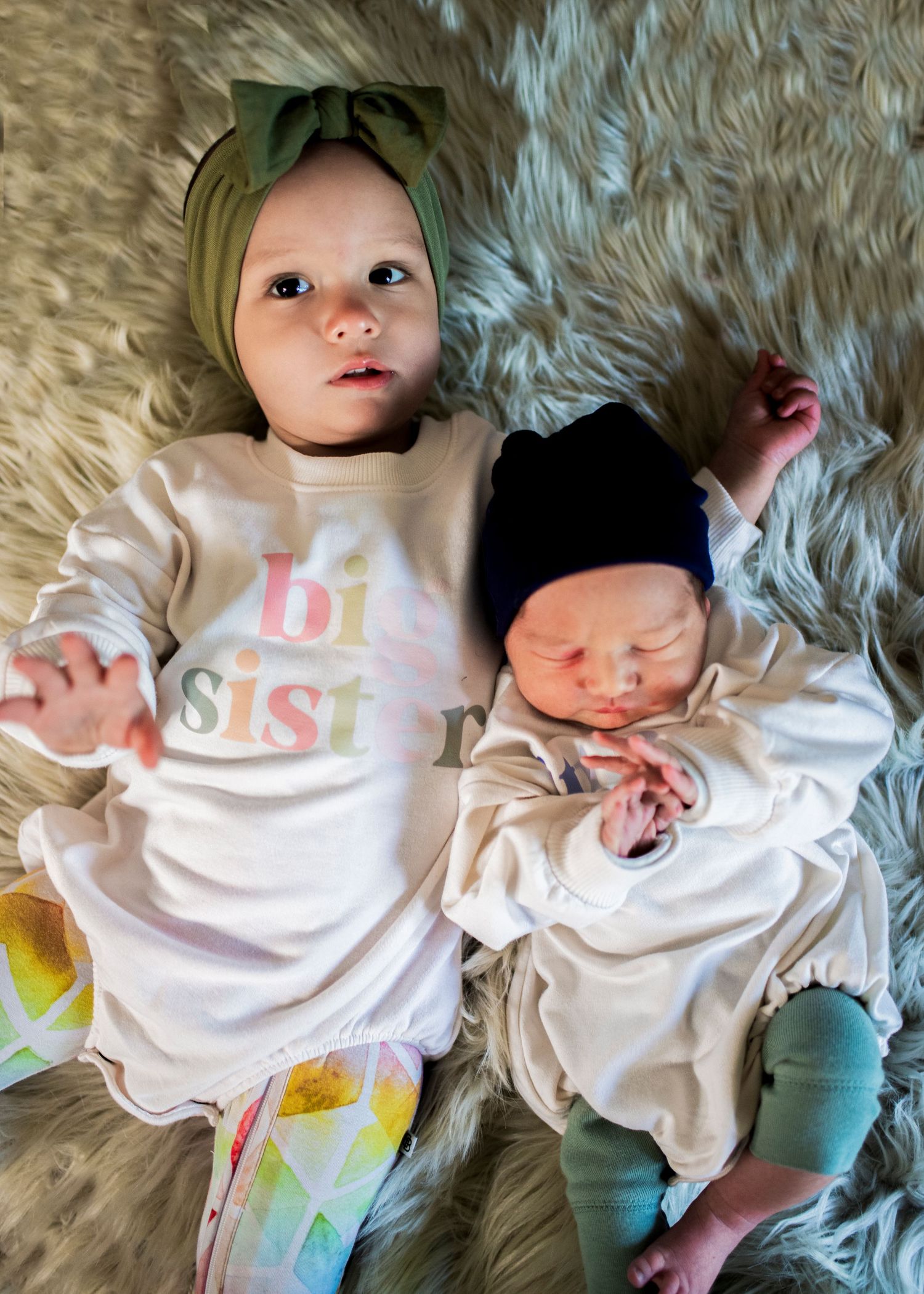 New big sister lays on a furry rug with her baby brother in their New Jersey home.