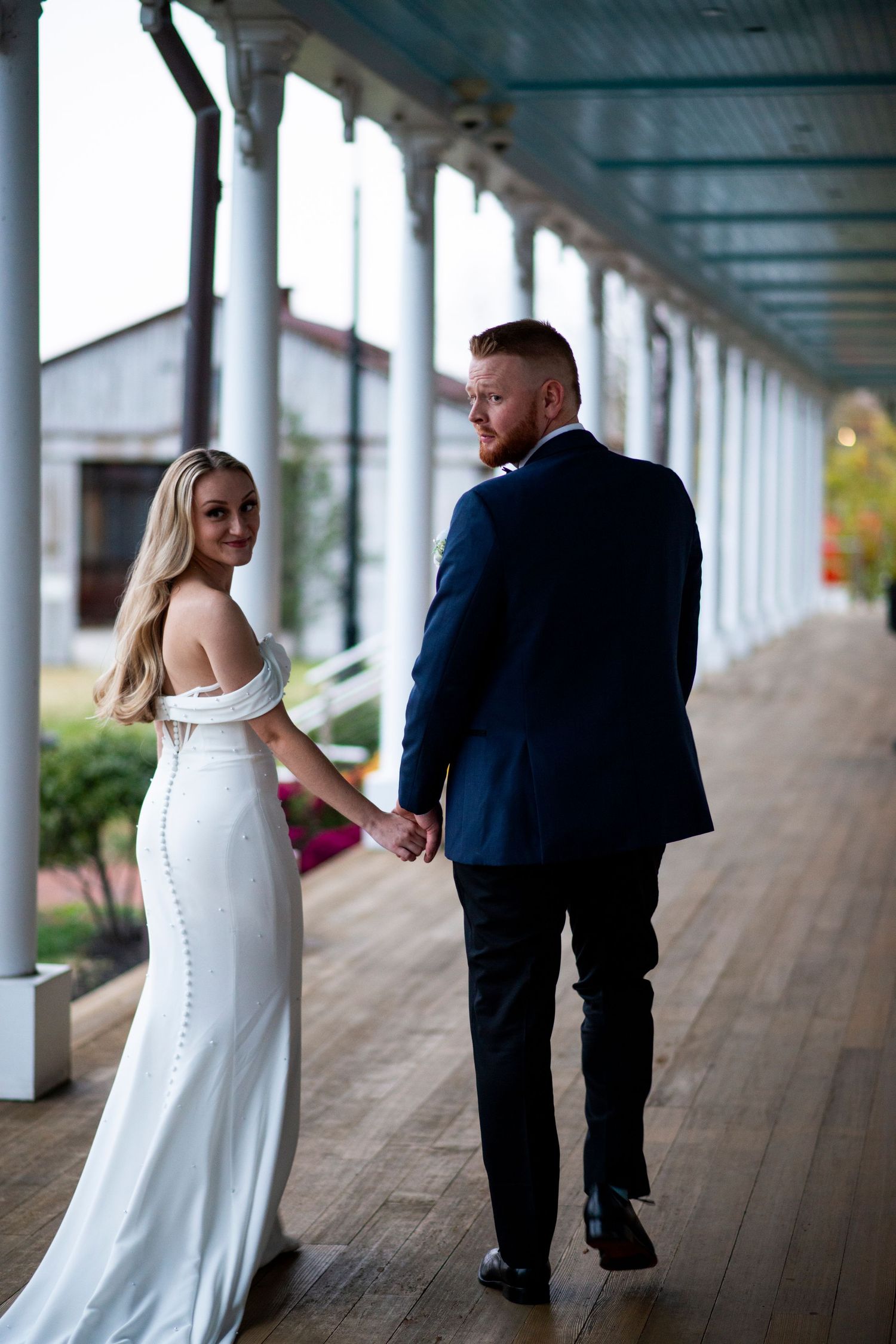 Bride and groom look back during walking portrait outside at Lazaretto Ballroom in Pennsylvania.