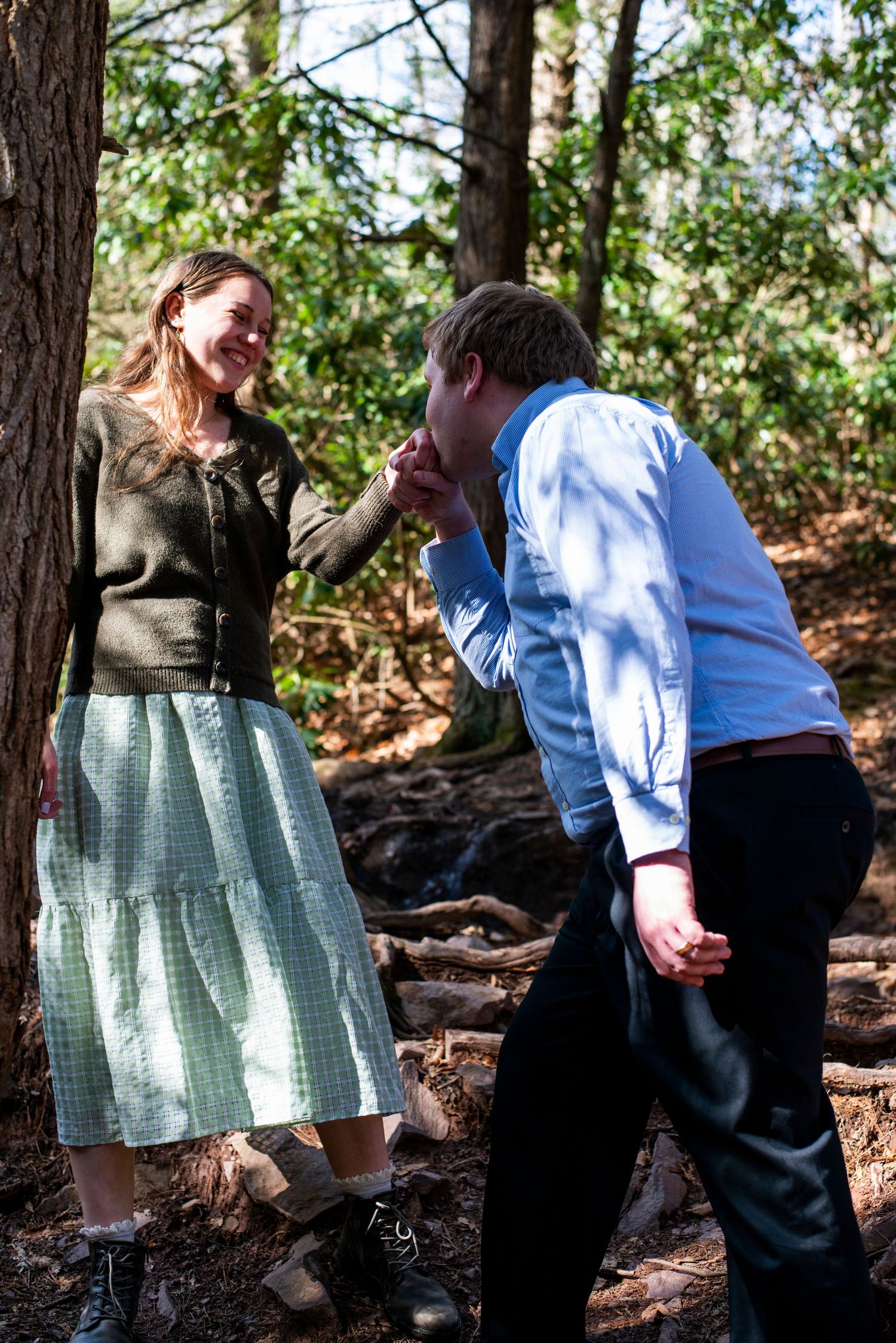 Groom bends to kiss bride's hand on the trail at Hawk Falls in Pennsylvania.