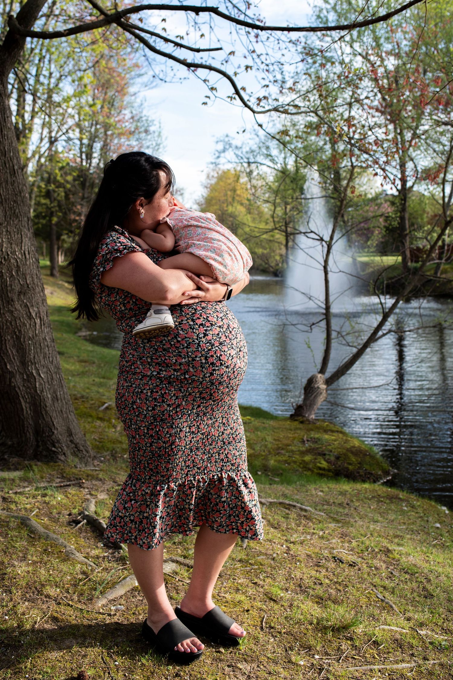 Pregnant mother holds her toddler and looks out on the lake in Marlton, New Jersey.
