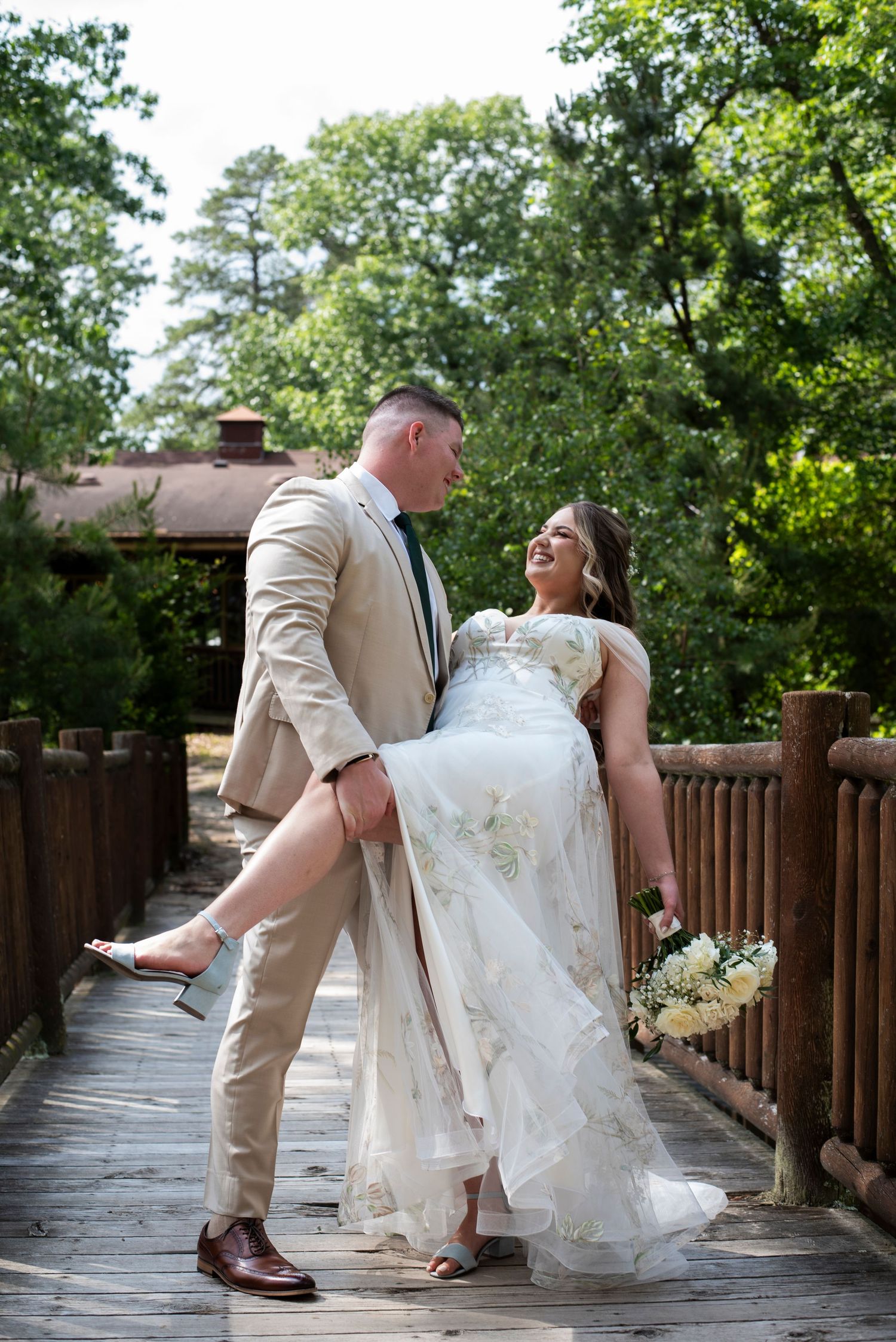 Groom holds bride's leg for a dip on the bridge at Camp Matollionequay in Medford, NJ.