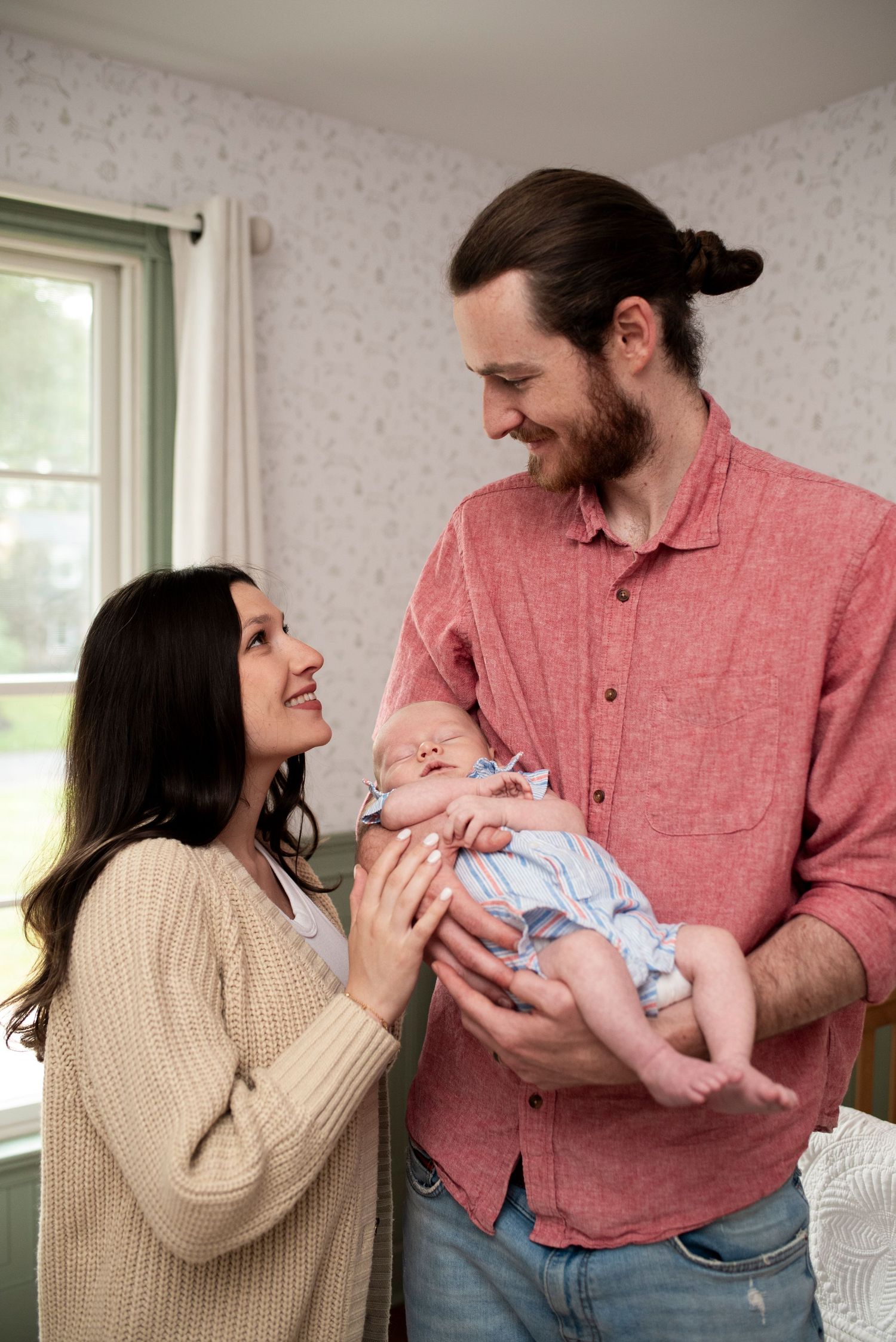 Parents smile at each other holding newborn between them in Medford, New Jersey.