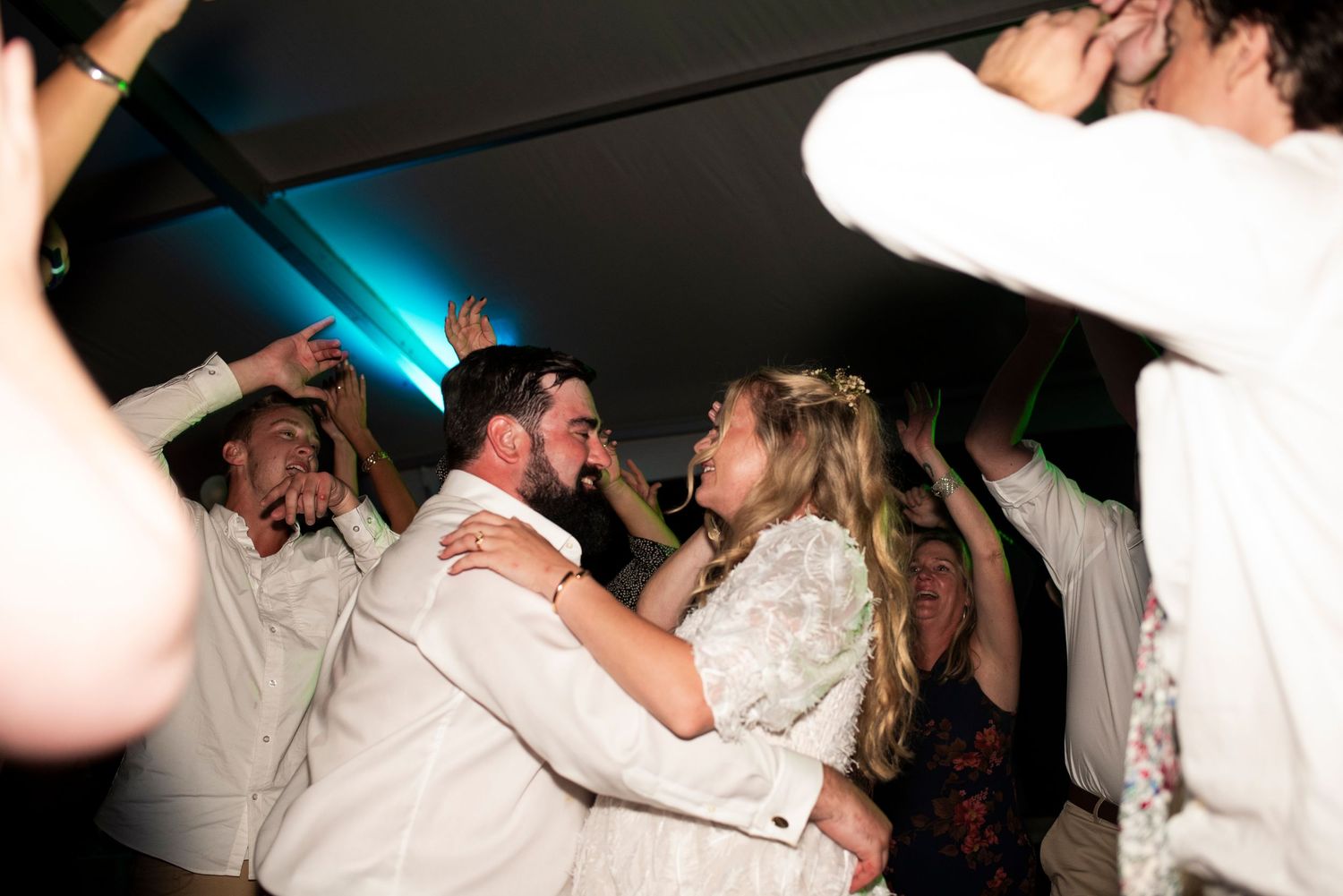 Bride and groom smile and dance surrounded by friends on the dance floor at their wedding reception in Coatesville, Pennsylvania.
