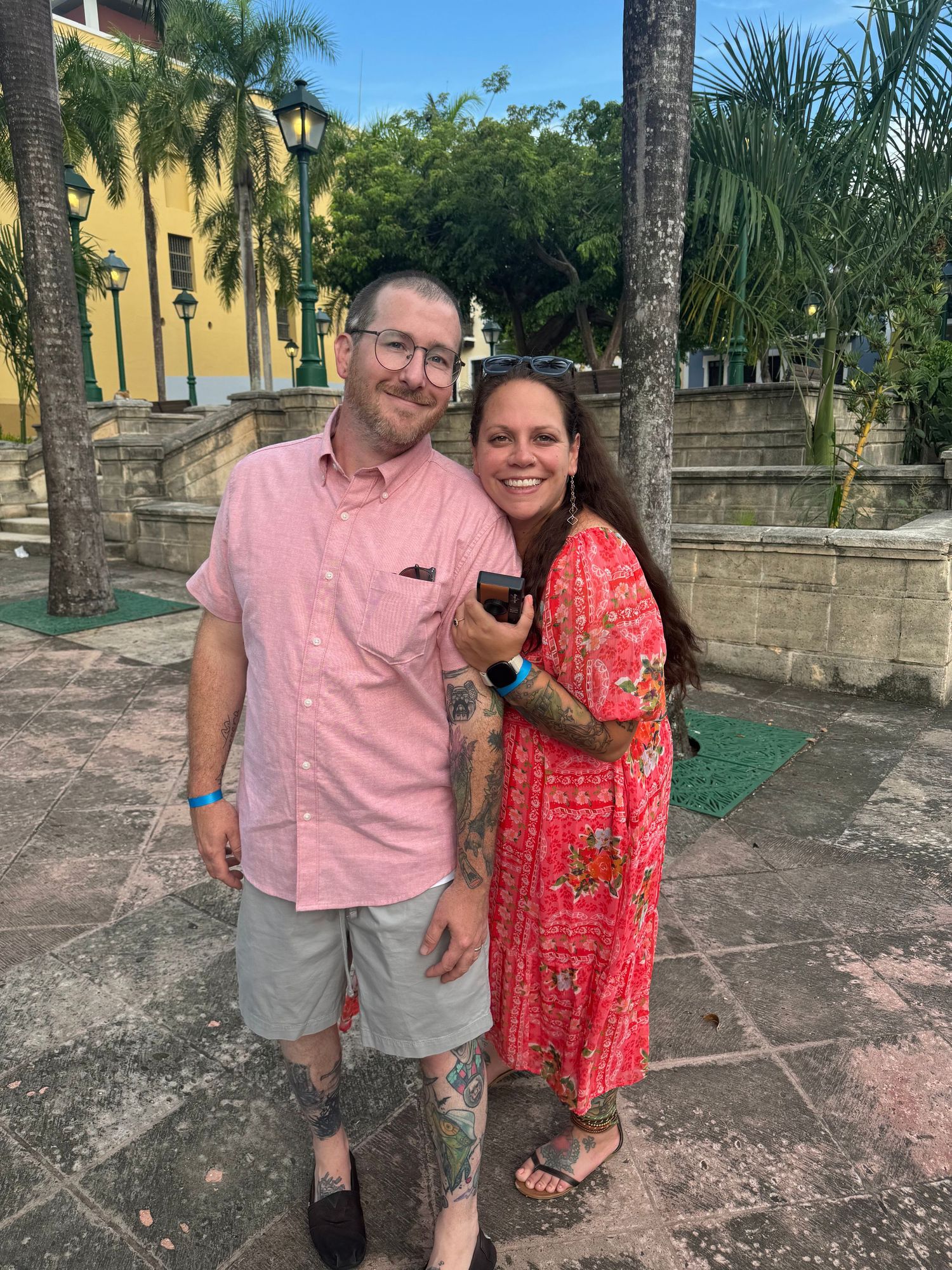 Smiling couple in bright outfits stand arm in arm in Old San Juan, Puerto Rico.
