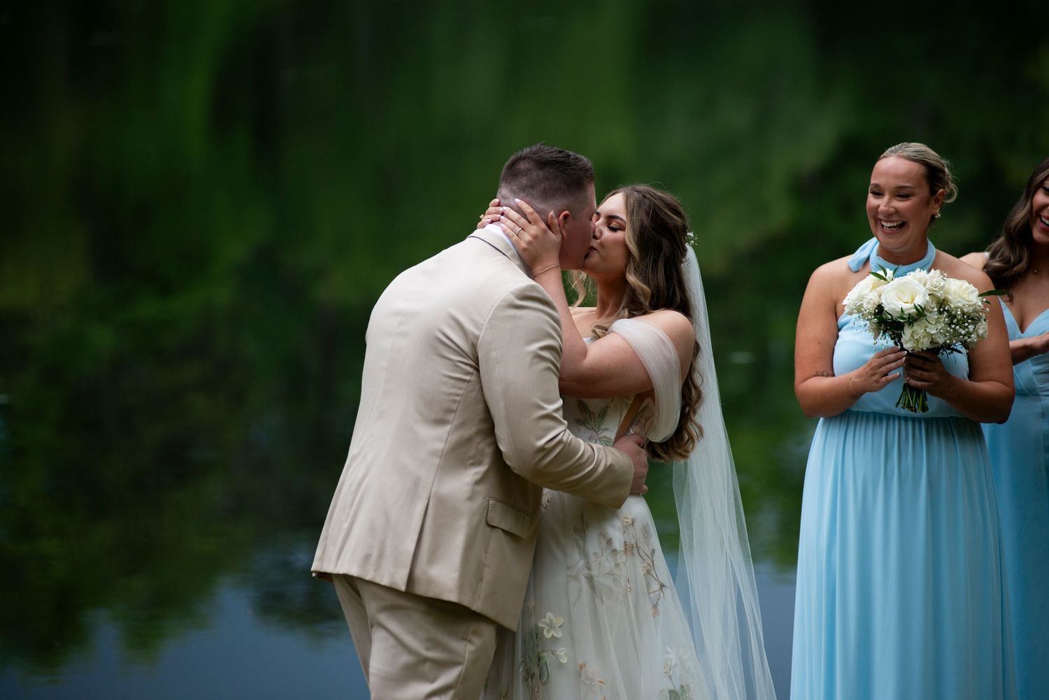Bride and groom share first kiss during lakeside ceremony at Camp Matollionequay in Medford, New Jersey.