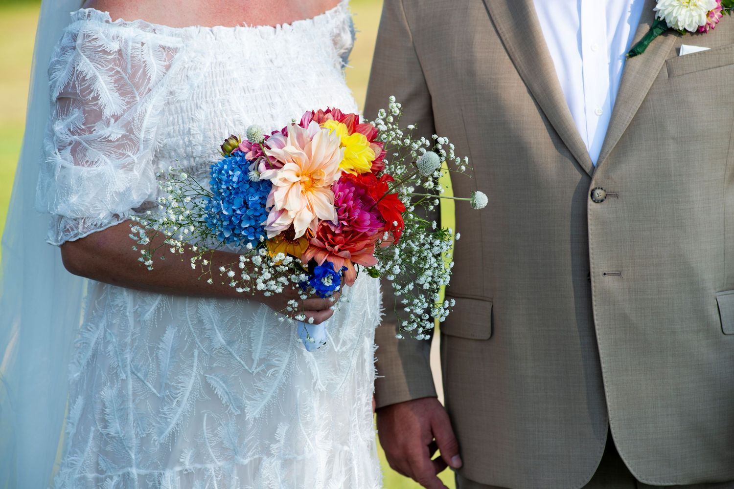 Close up of bride and groom from neck to waist detailing bride's bouquet against their outfits during wedding ceremony in Coatesville, PA.