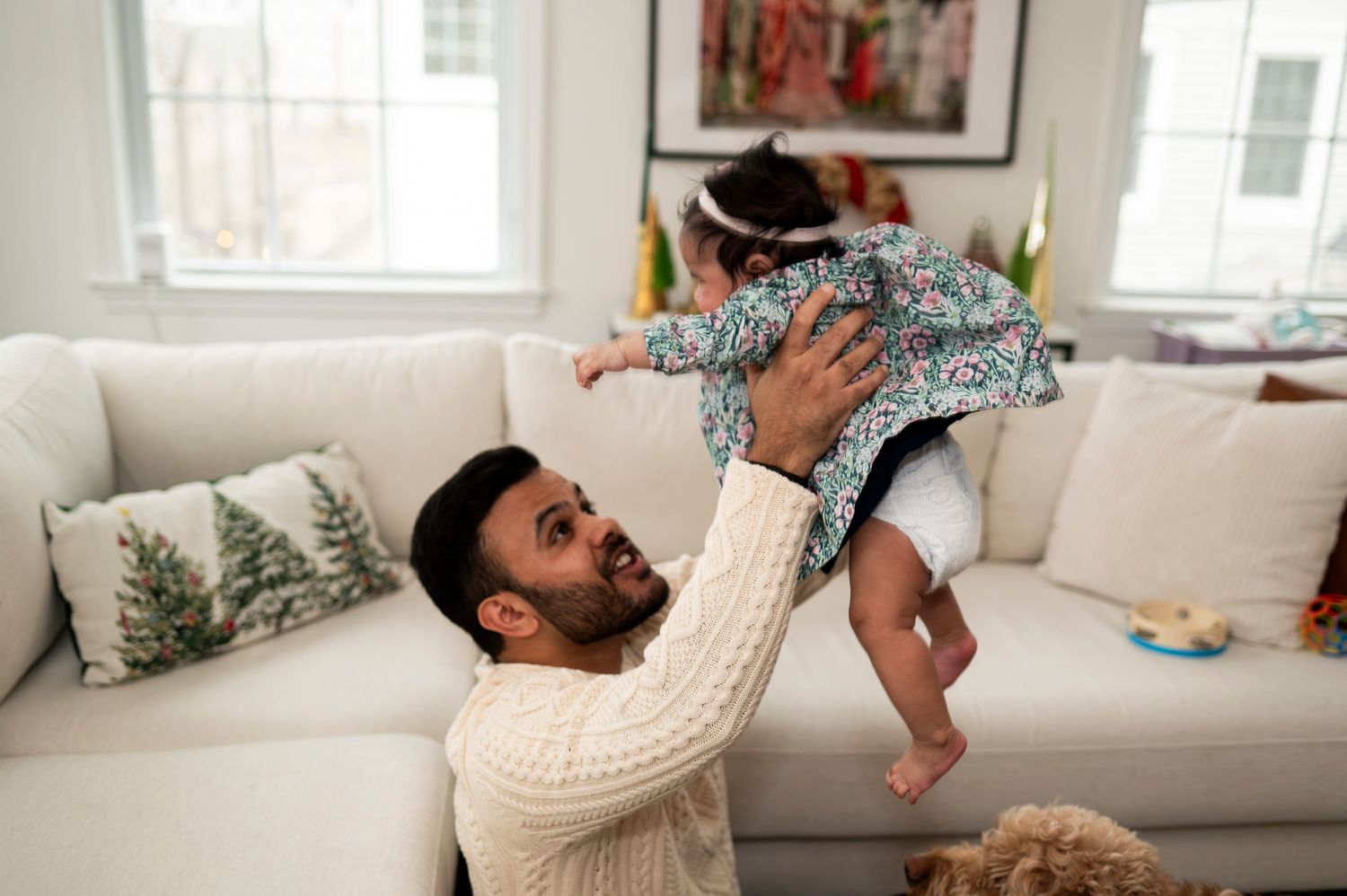 Father holds his newborn daughter above his head at home in New Jersey.
