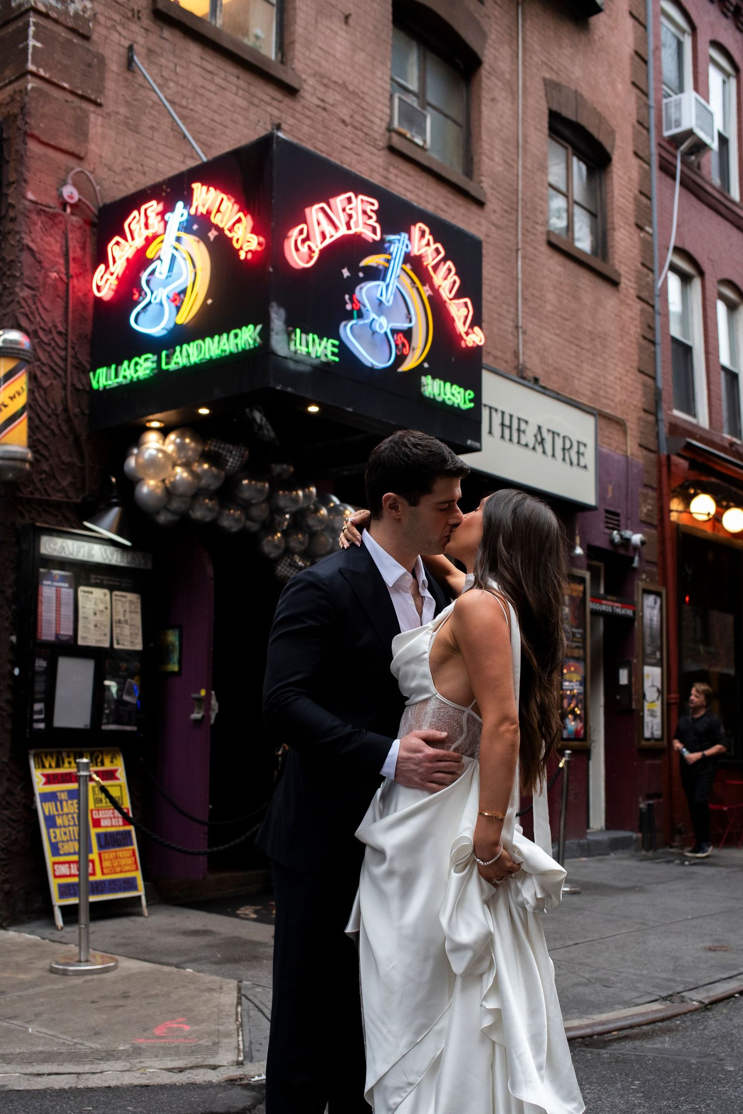 Bride and groom smile at each other in a rainy New York City street outside of Cafe Wha? before their wedding reception.