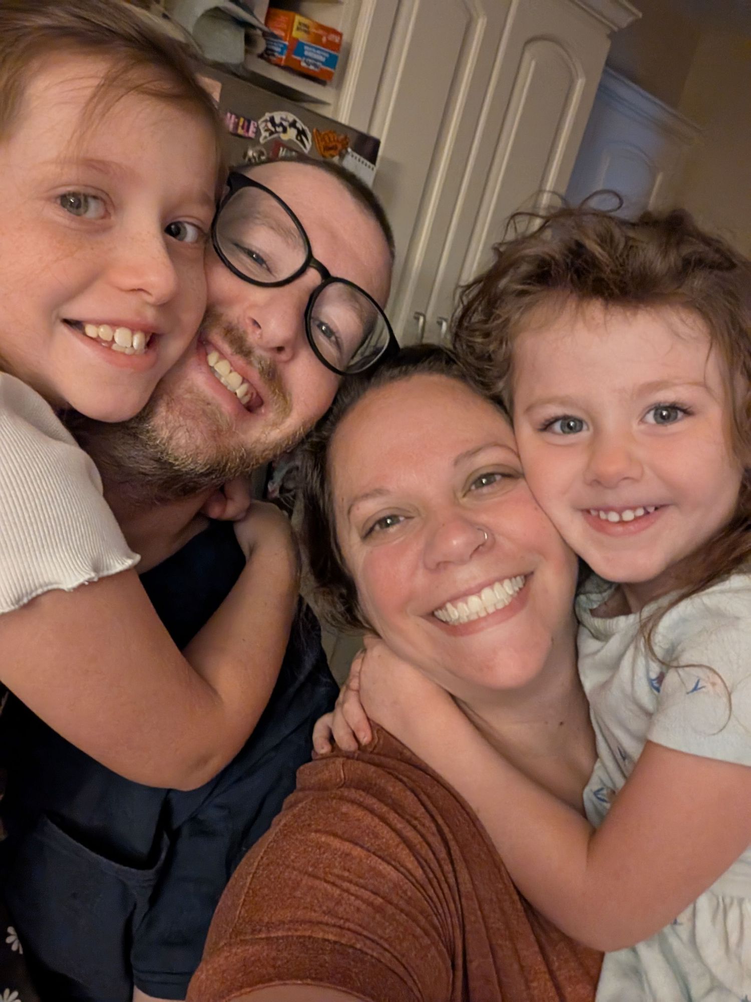 Selfie of family of four smiling at the camera.