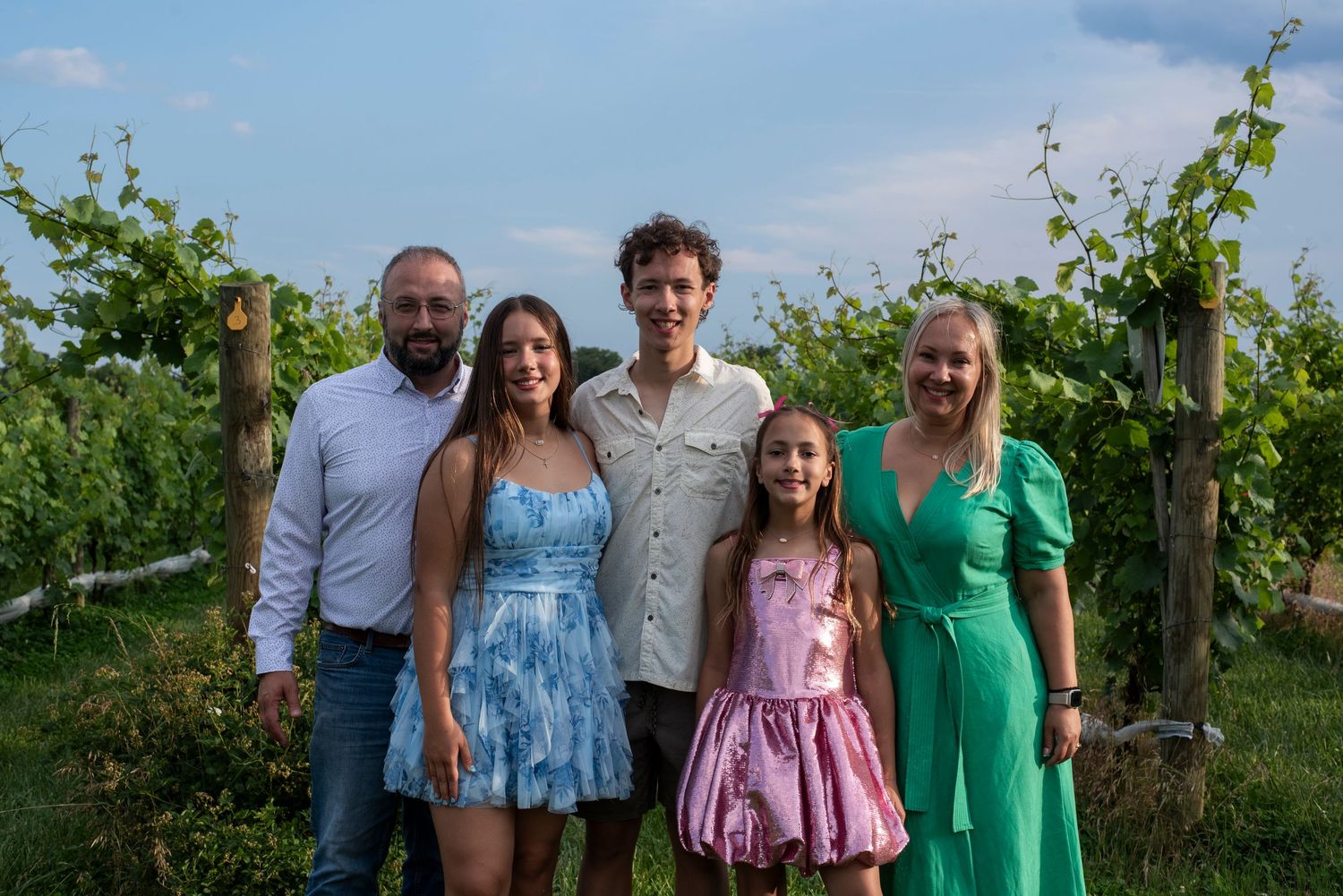 Family of five smiles for a portrait in the vineyard at Stokelan Winery in Medford, New Jersey.