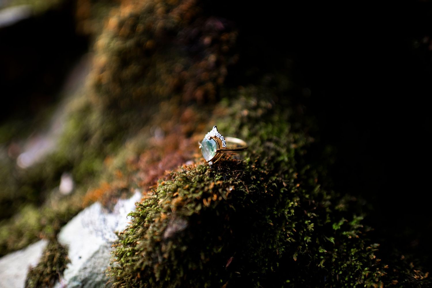 Emerald and diamond engagement ring posed on dark moss at Hawk Falls, Pennsylvania,