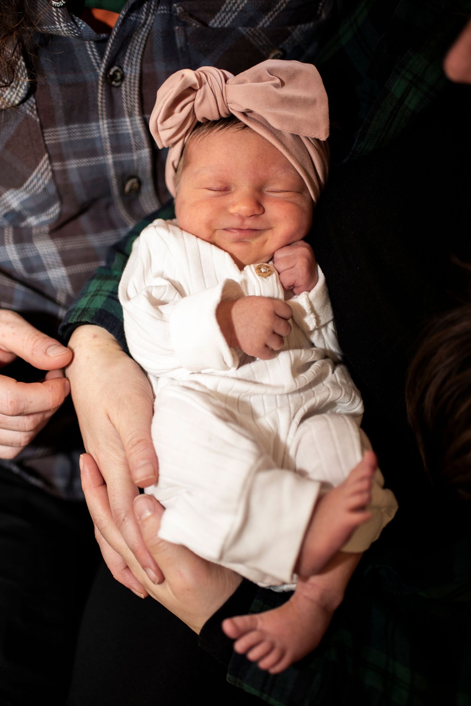 Portrait of newborn baby girl in parent's arms.