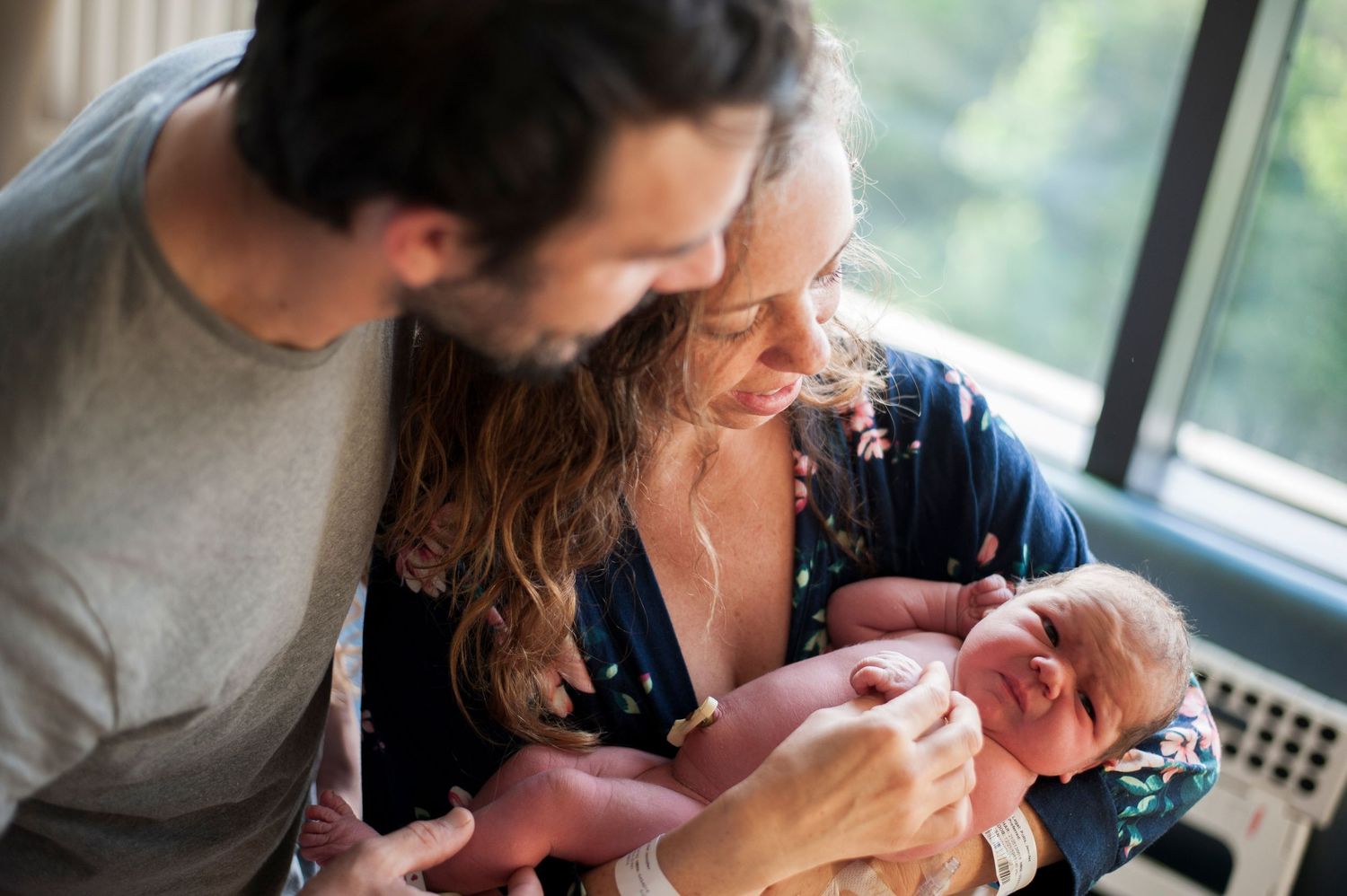 Parents smile down at newborn baby in hospital.