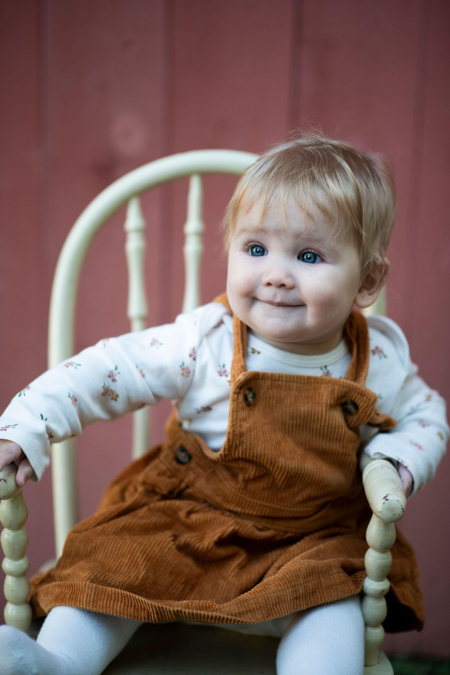 Baby sits in a white chair in front of a red barn at Croft Farm in Cherry Hill, NJ.