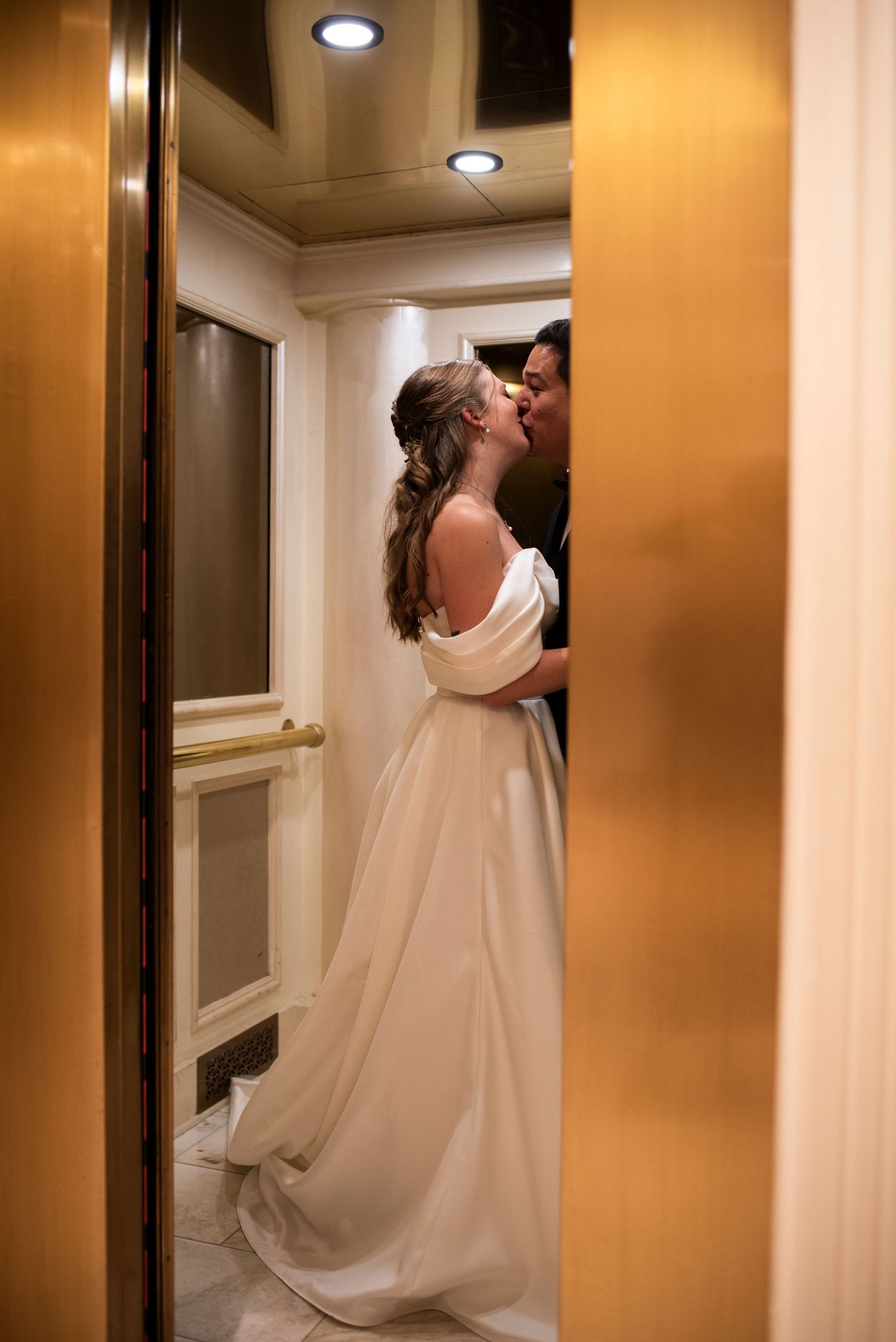 Bride and groom kiss as elevator doors close during wedding reception at The Mansion in Voorhees, New Jersey.