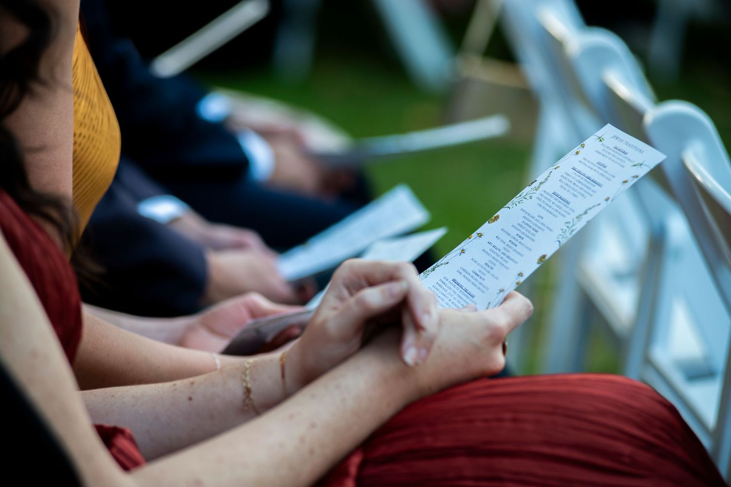 Close up of guest's hands holding wedding program at ceremony at Bartram's Garden in Philadelphia, PA.