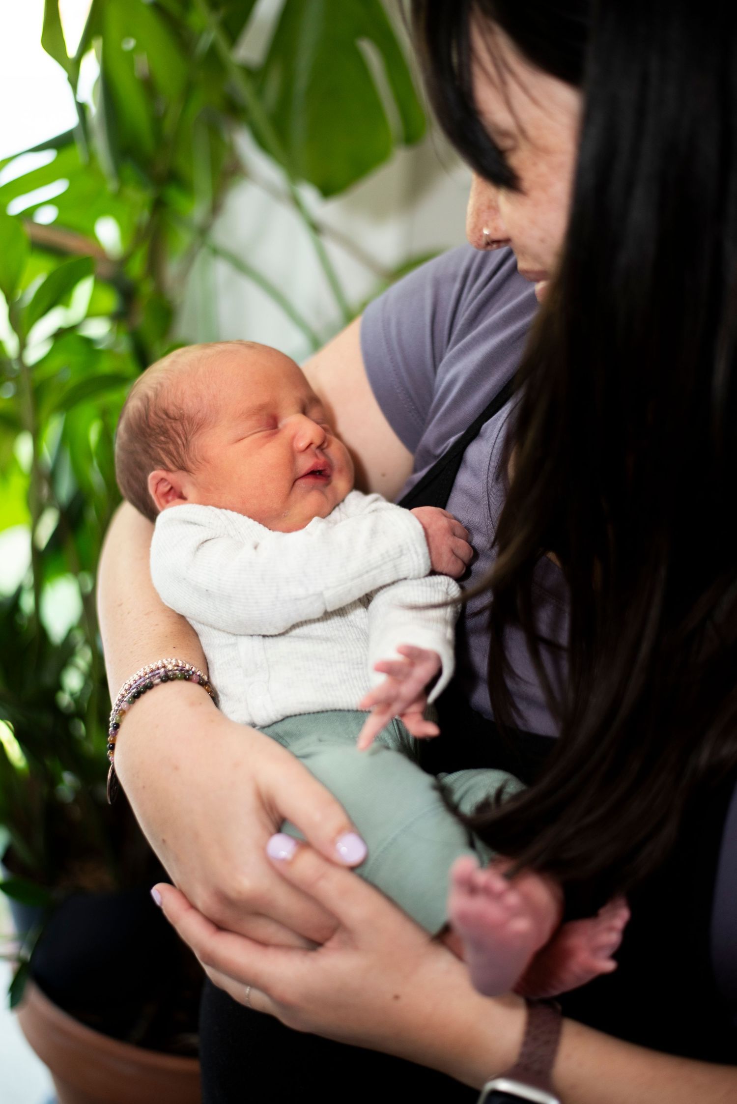 New mother looks down at her newborn son in her arms.