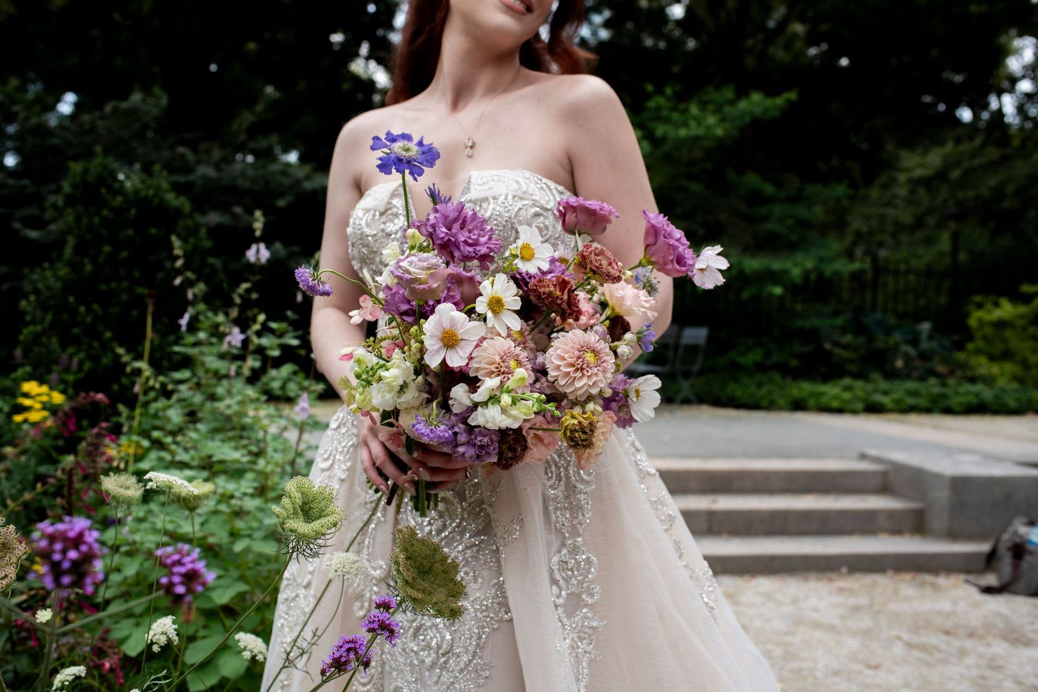 Close up of bride's bouquet as she smiles in the garden of the Rodin Museum in Philadelphia.