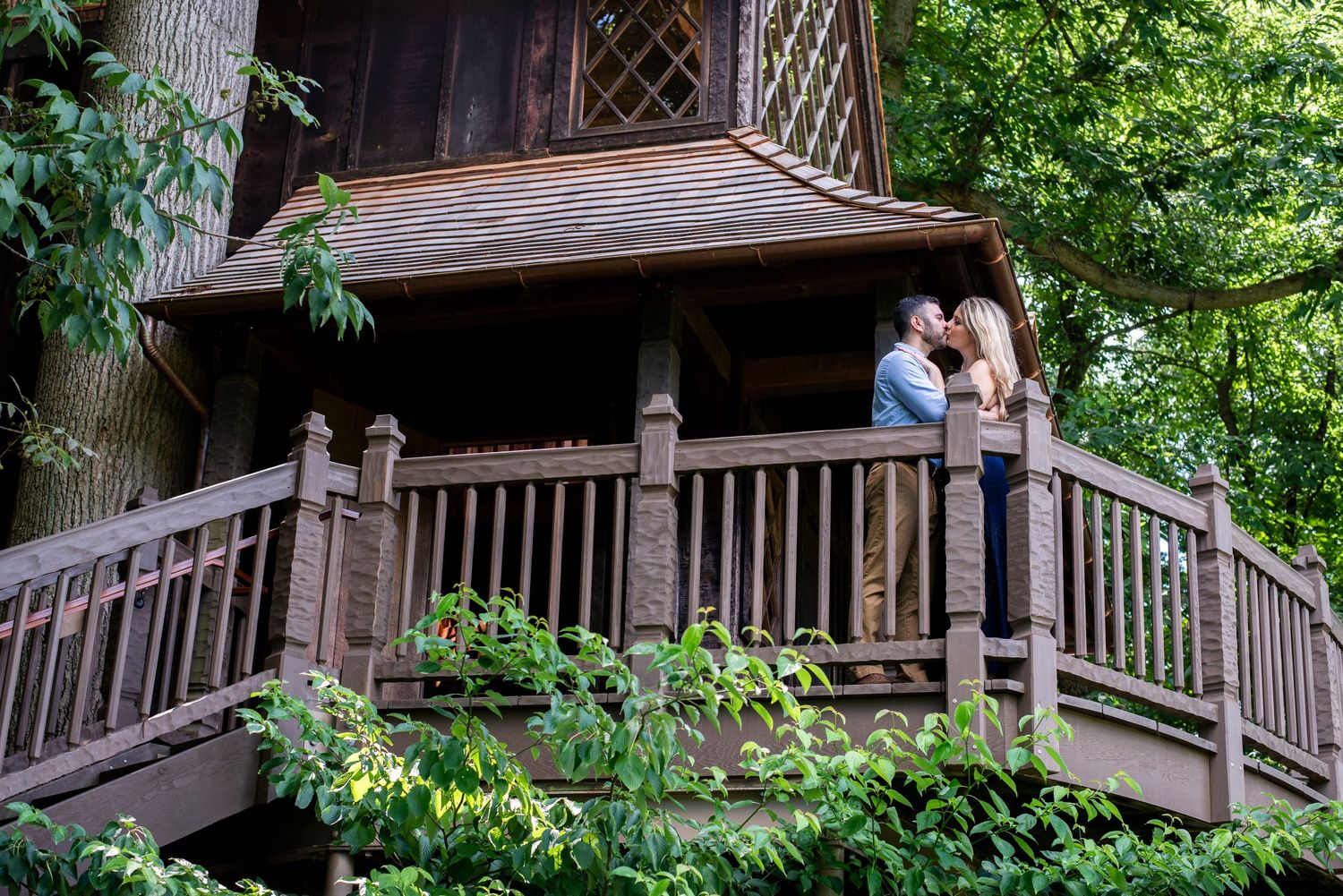 Engaged couple kisses on the balcony of a treehouse  at Longwood Gardens in Pennsylvania.