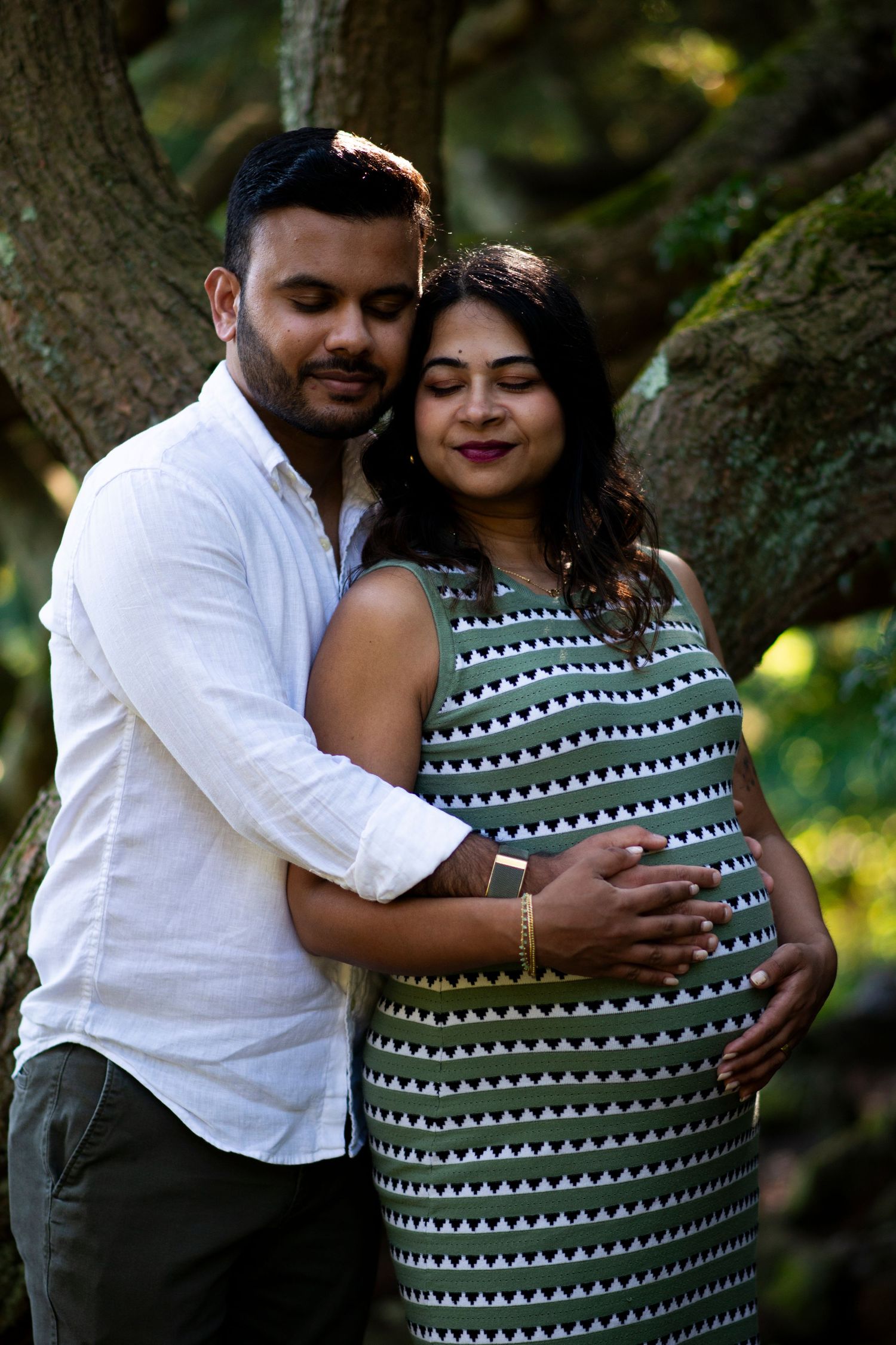 Pregnant mother leans into her husband with eyes closed at Deep Cut Gardens in New Jersey during maternity shoot.