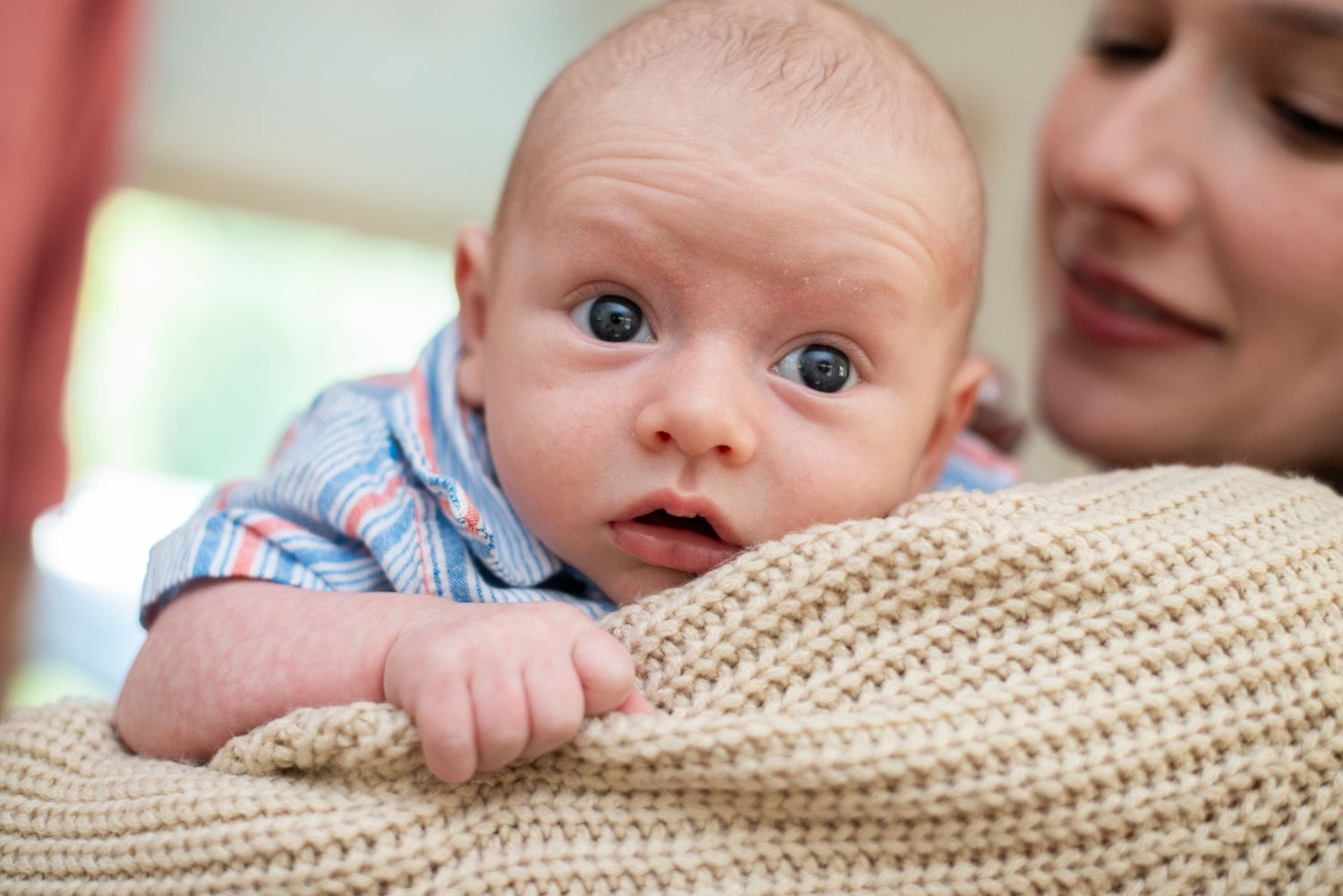 Closeup of newborn baby boy looking over his mom's shoulder.