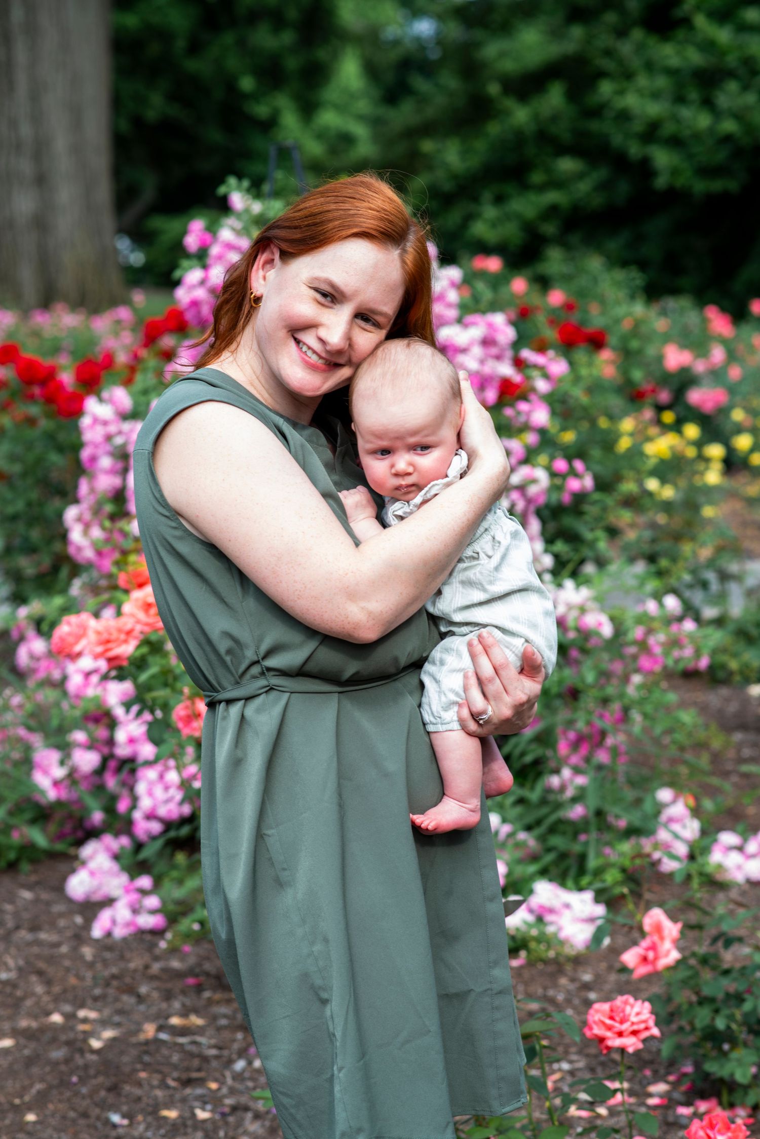 Mom smiles with infant daughter in the Rudolf W. van der Goot Rose Garden at Colonial Park in Somerset, NJ.