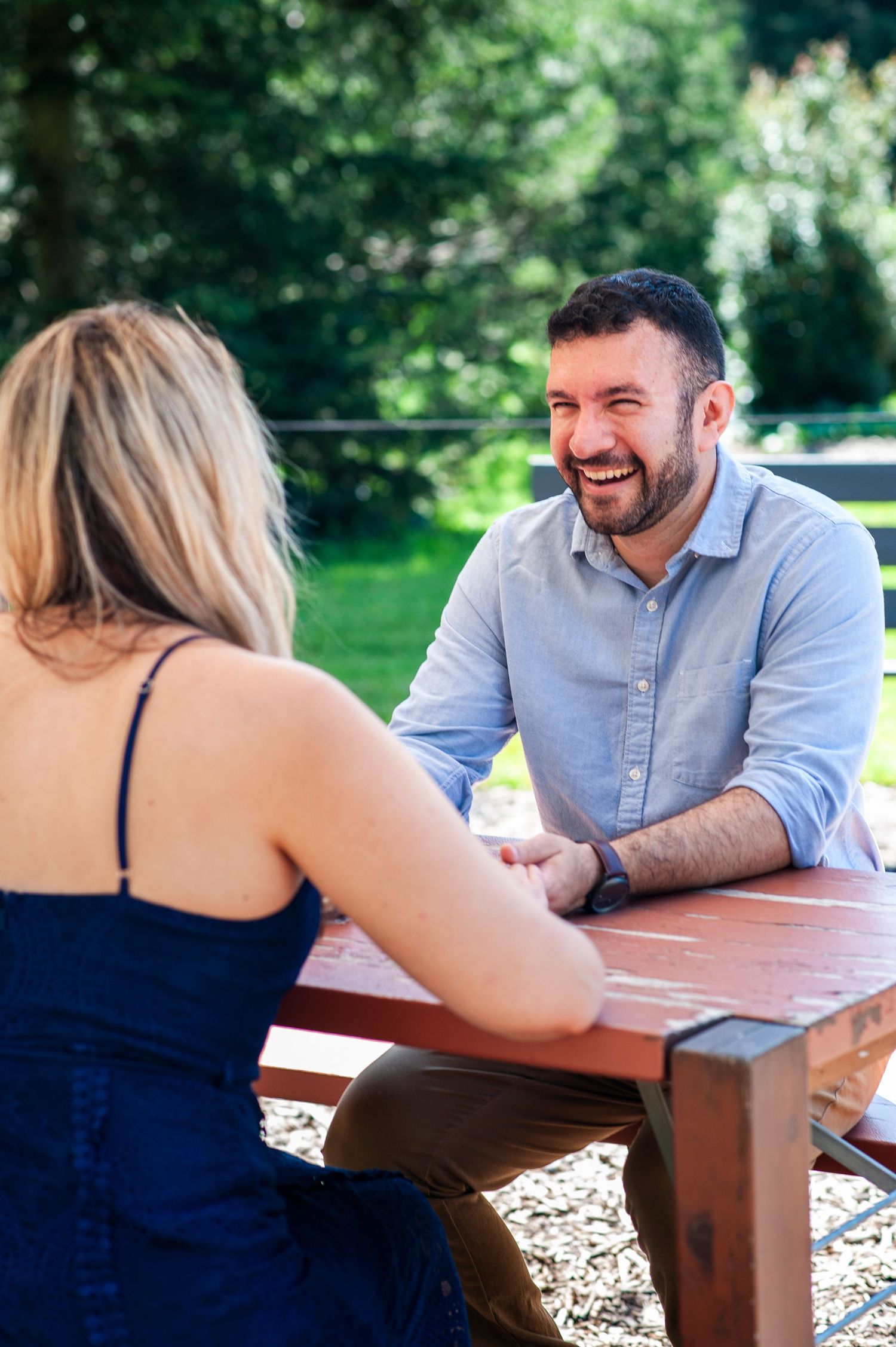 Man smiles at his future bride across a table at Longwood Gardens in Pennsylvania.