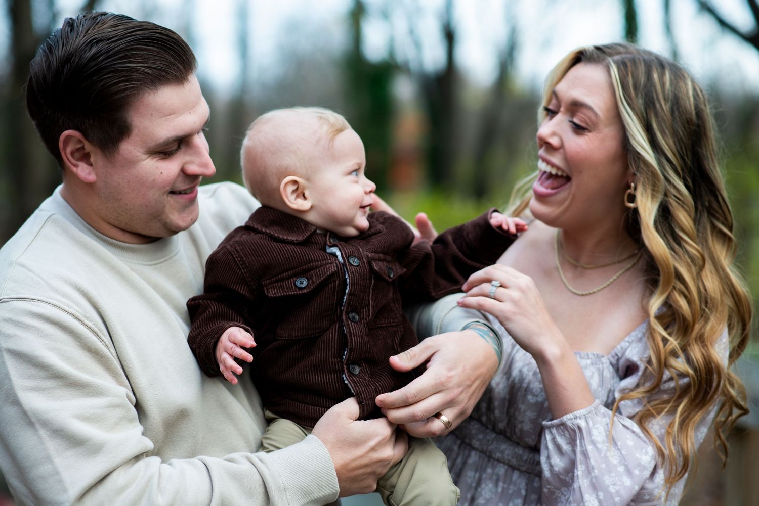 Parents smile and laugh with their toddler for portrait at Croft Farm in Cherry Hill, NJ.
