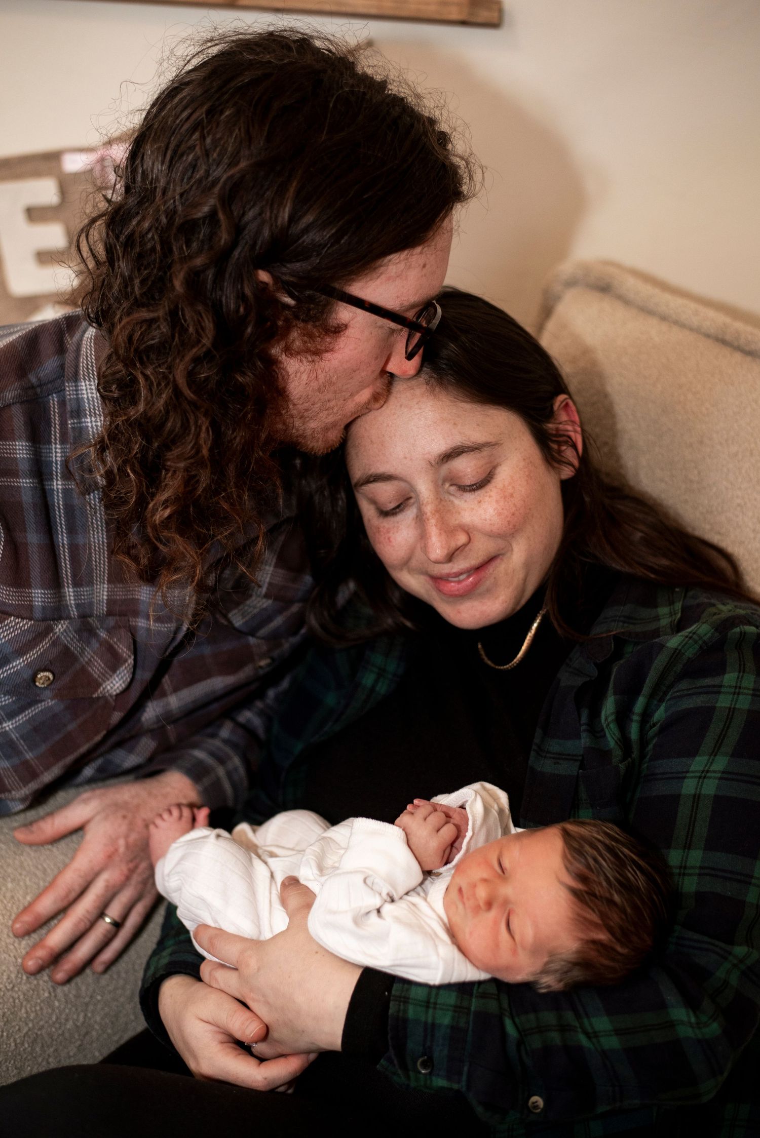 New parents snuggle with their newborn daughter, admiring her, in their home in New Jersey.